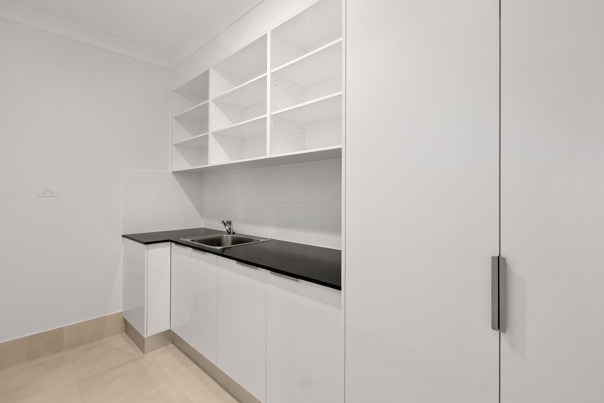 A Minimalist Laundry Room With White Cabinetry — Ashlee Jones Homes in Gordonvale, QLD