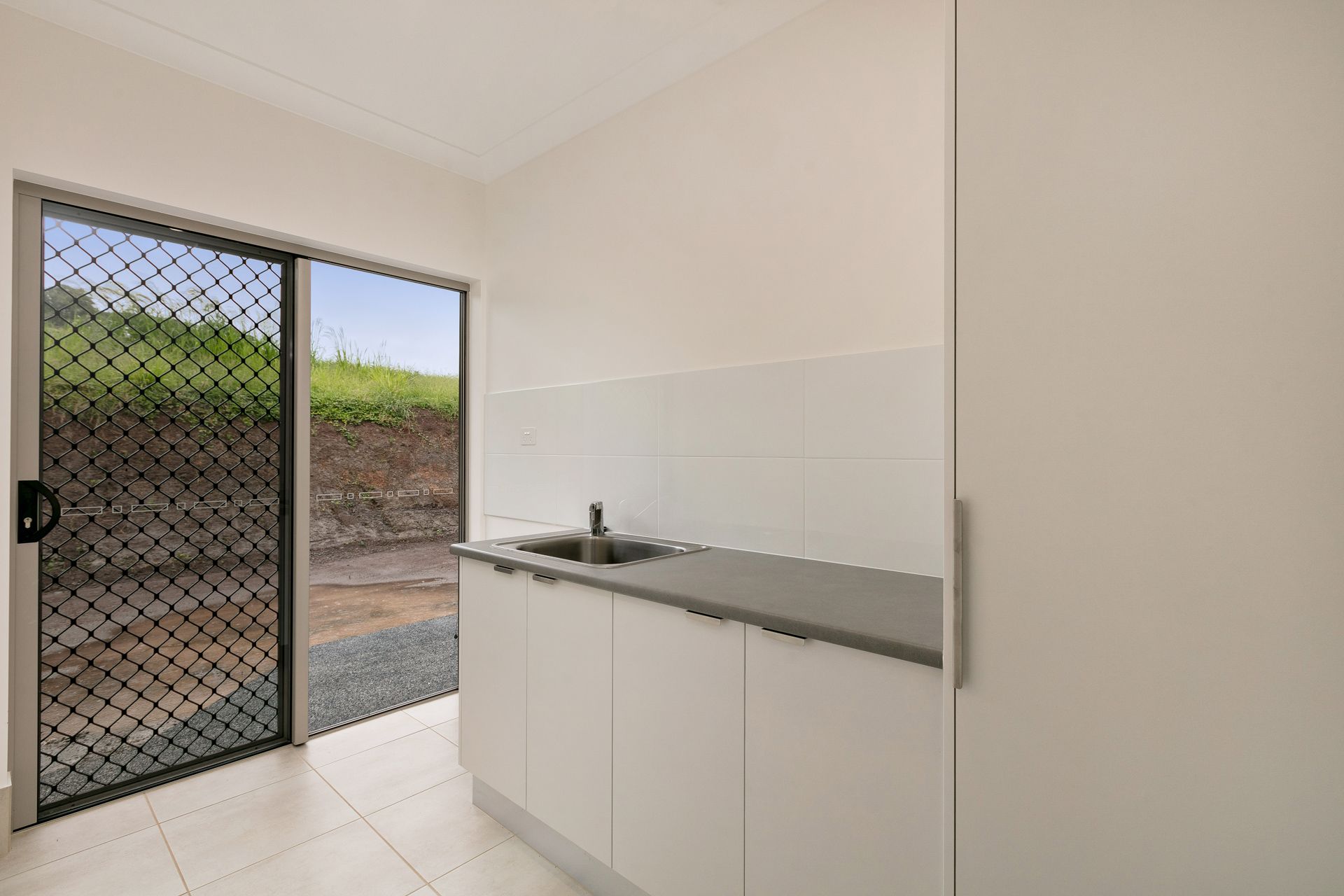 A Small Kitchen Area With White Cabinets and a Sink, Next — Ashlee Jones Homes in Gordonvale, QLD