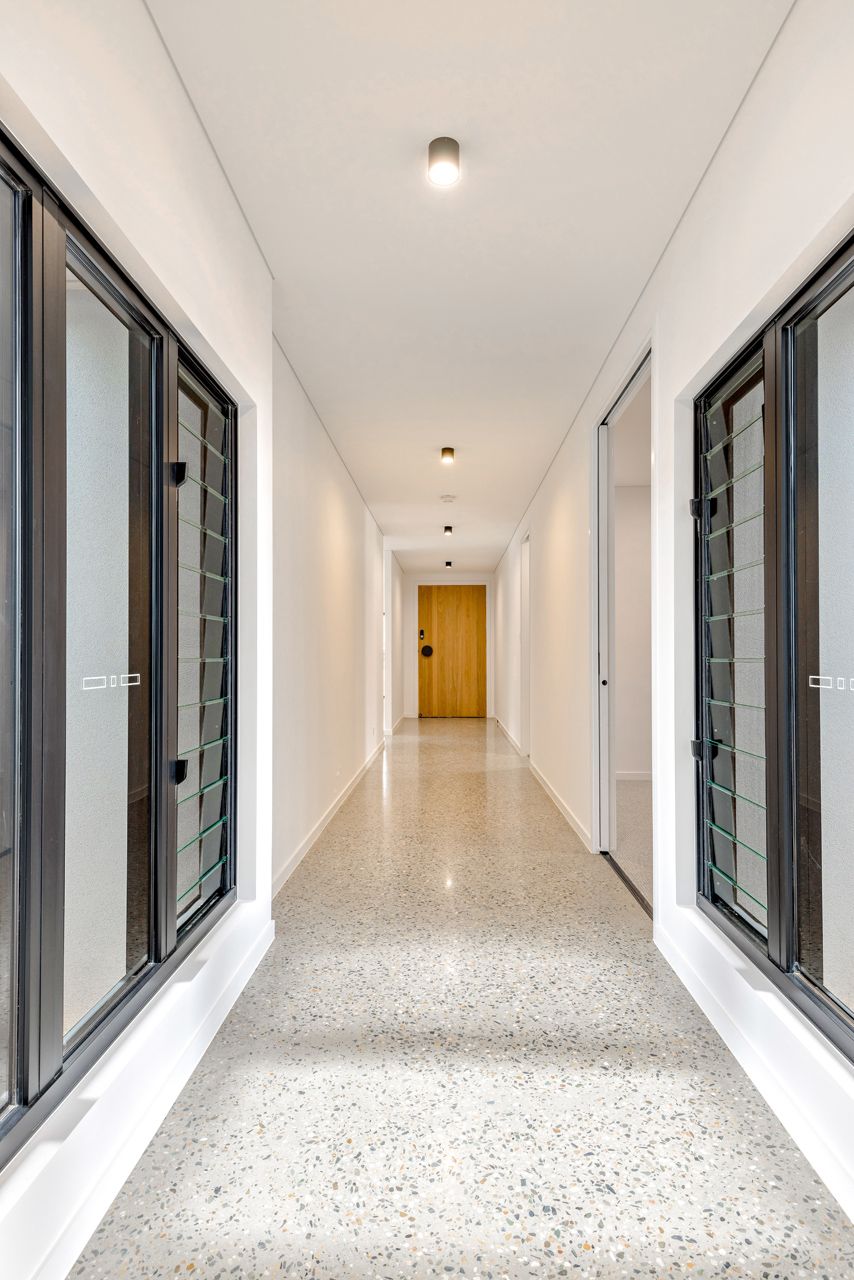 A Brightly Lit, Symmetrical Hallway With White Walls — Ashlee Jones Homes in Gordonvale, QLD