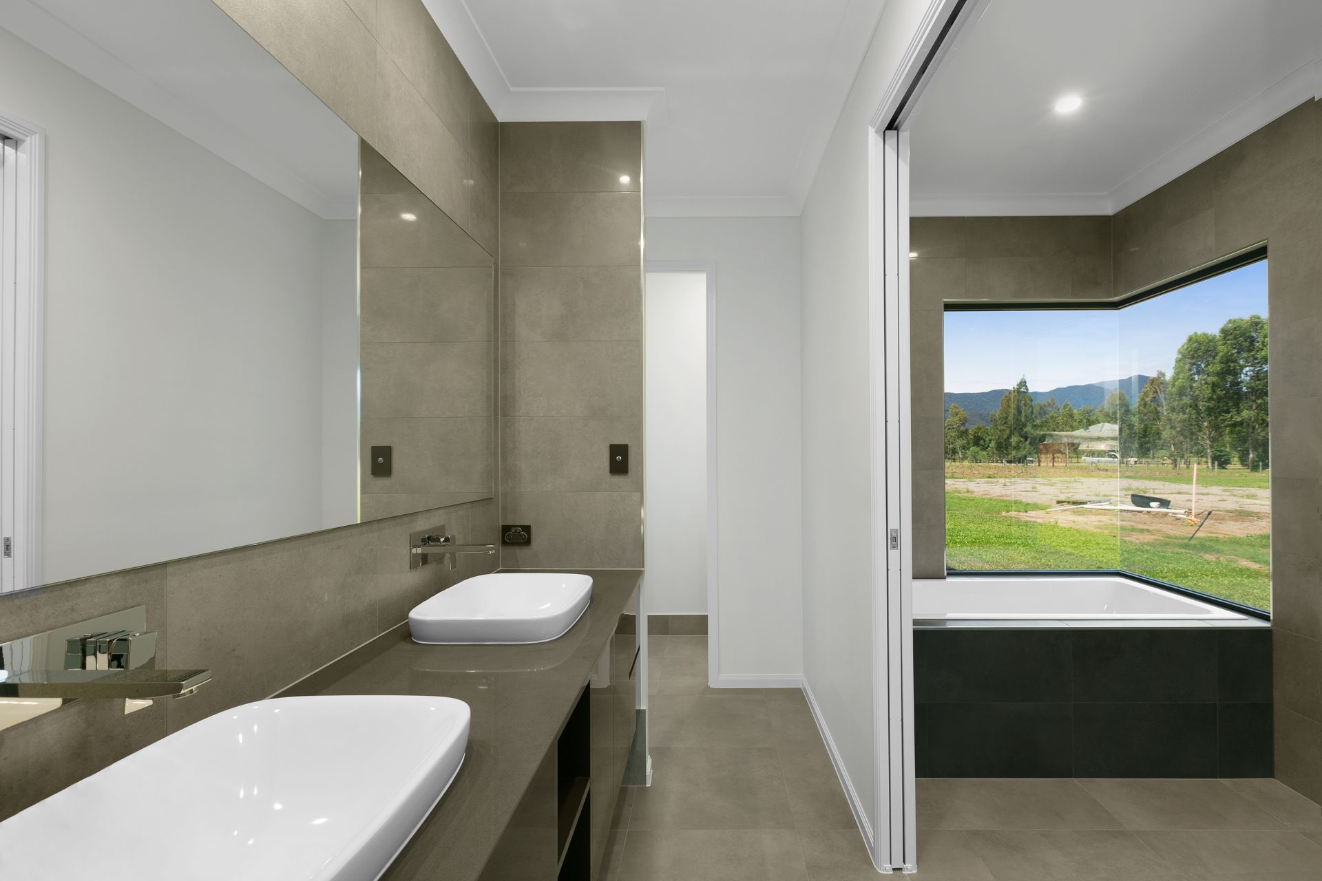 A Modern Bathroom With a Double Vanity Sink, and a Large Wall Mirror — Ashlee Jones Homes in Gordonvale, QLD