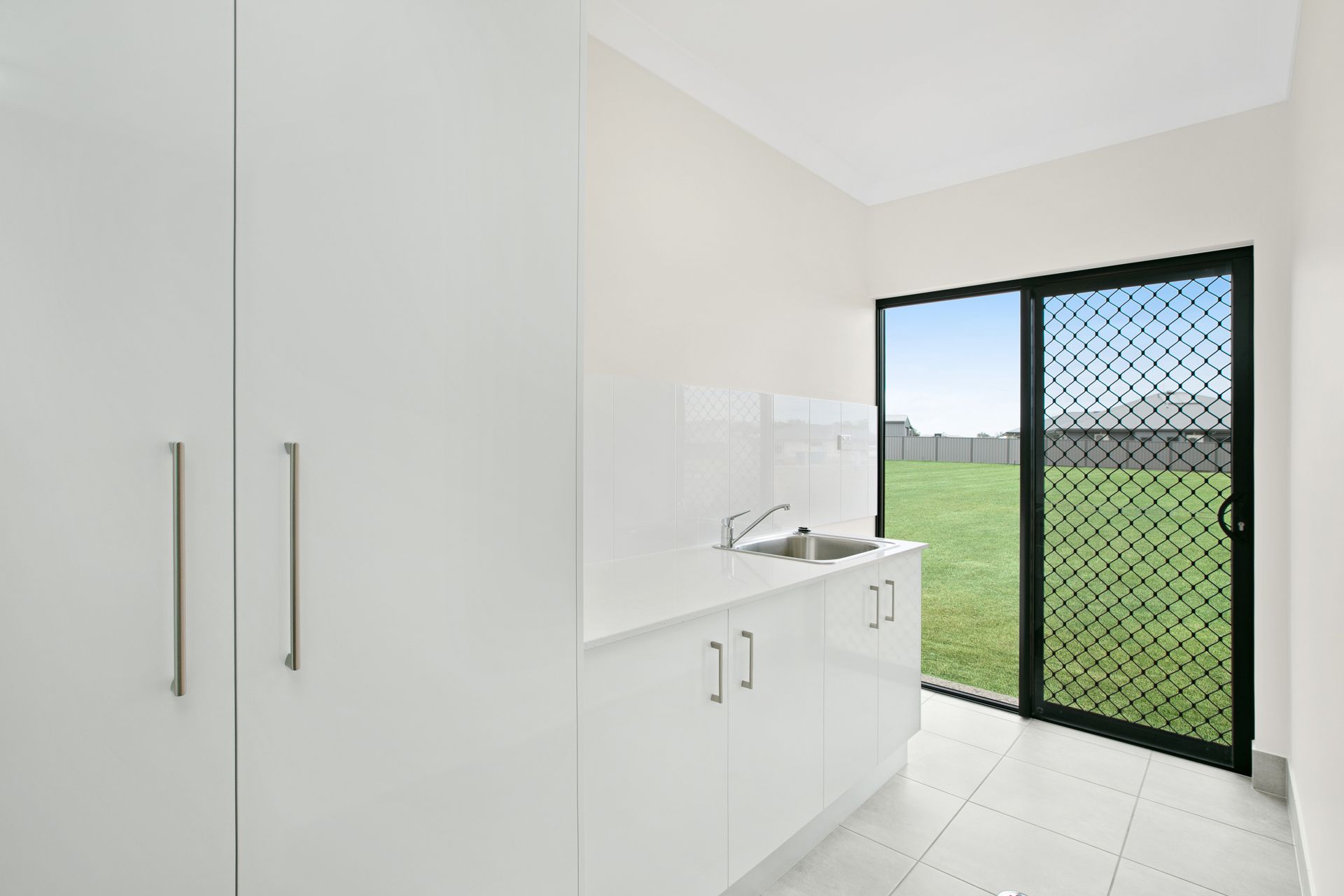 A Minimalist White Laundry Room or Kitchenette Featuring Cabinets — Ashlee Jones Homes in Gordonvale, QLD