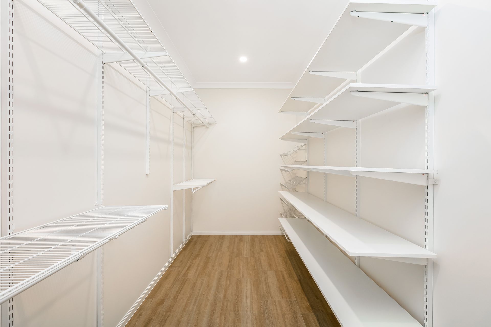 A Walk-in Closet With White Walls, Wood-look Flooring, and White Wire — Ashlee Jones Homes in Gordonvale, QLD