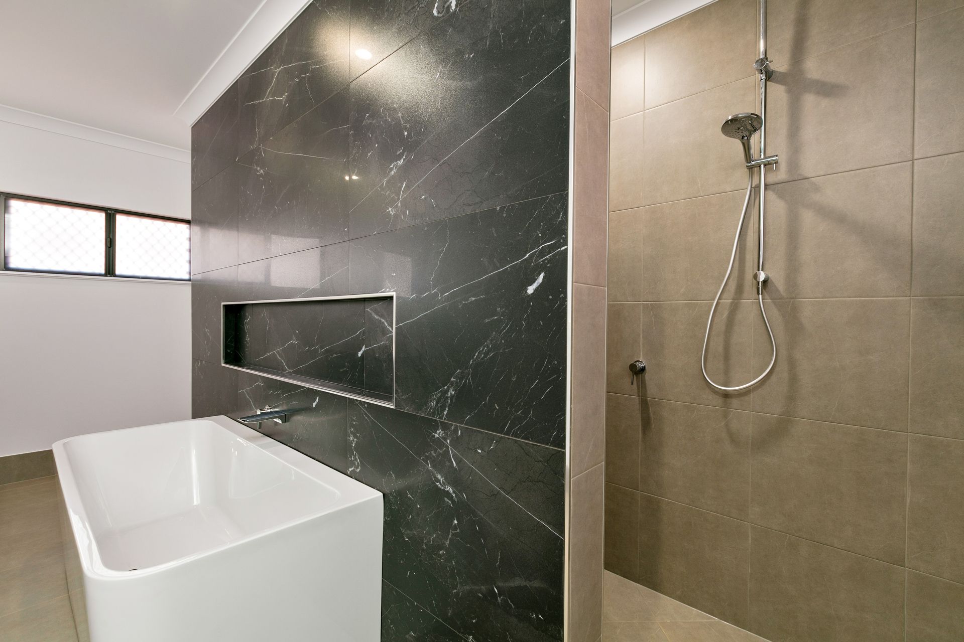 A Modern Bathroom Featuring a White Soaking Tub — Ashlee Jones Homes in Gordonvale, QLD