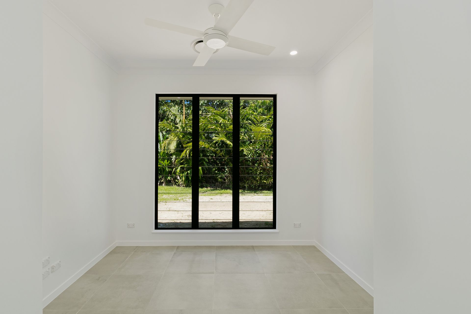 An Empty, Bright Room With White Walls, Light Tile Floors, a Ceiling Fan — Ashlee Jones Homes in Gordonvale, QLD