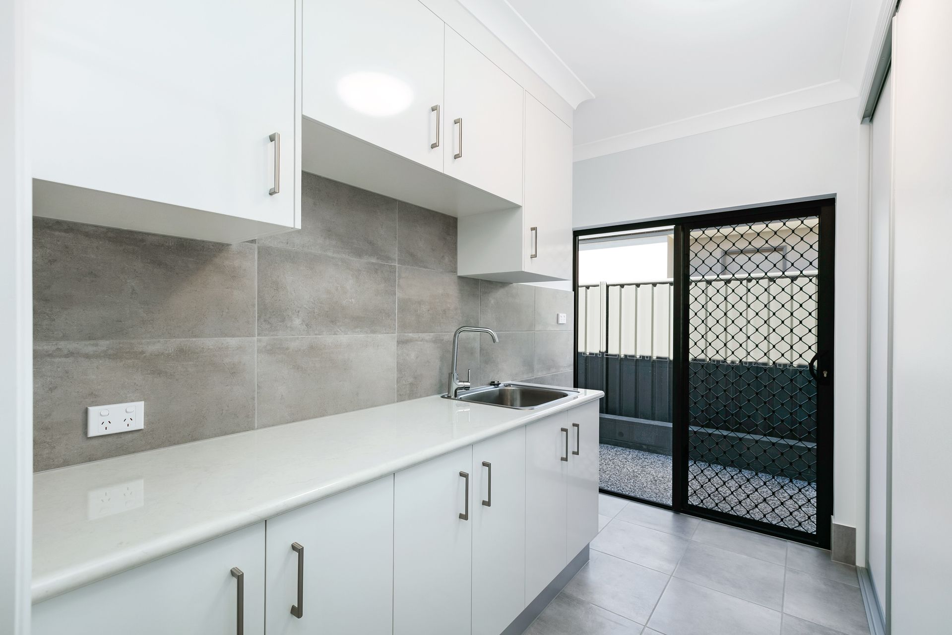 A Modern, Minimalist Laundry Room With White Cabinets — Ashlee Jones Homes in Gordonvale, QLD