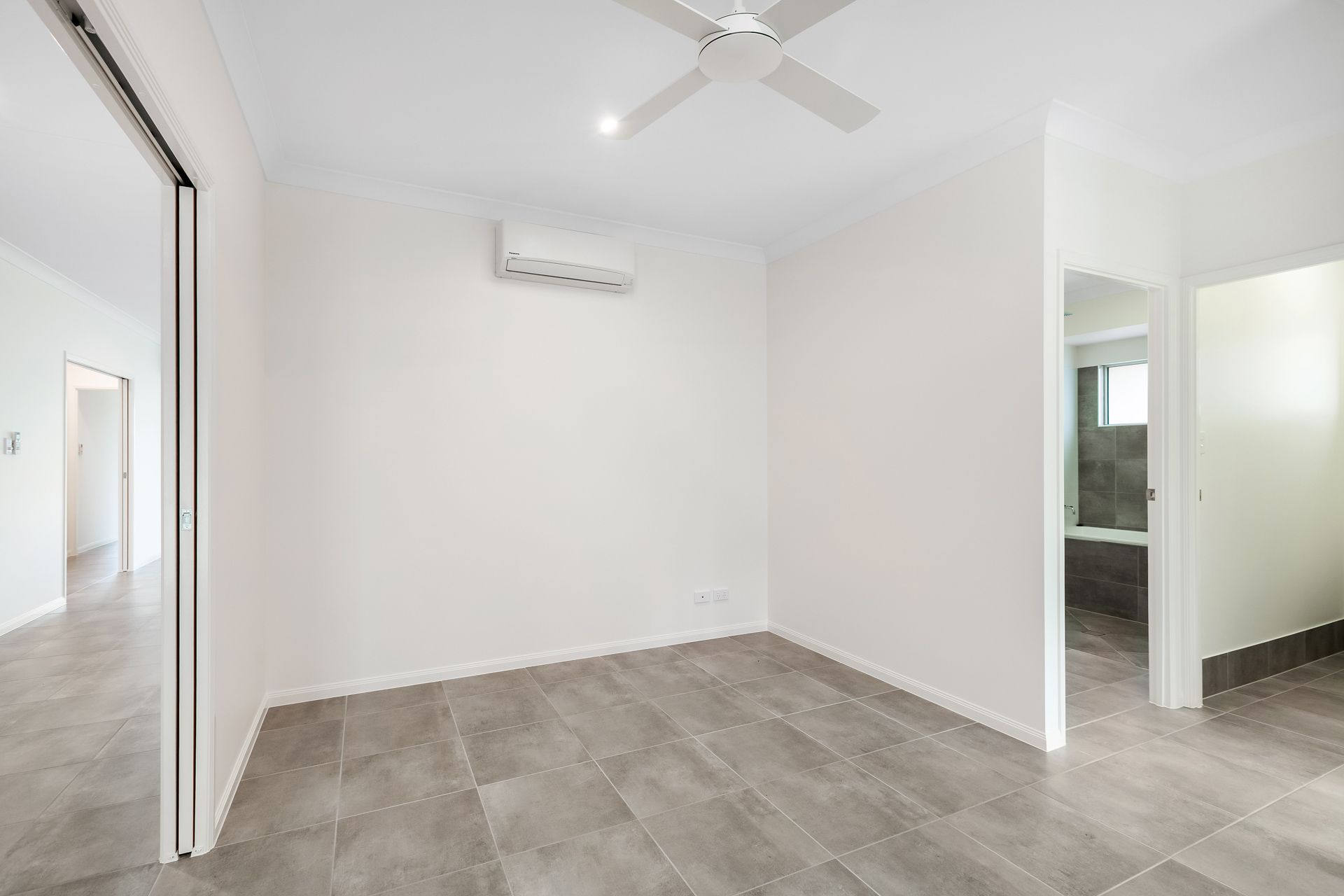 Empty Room With Light Walls and Large Grey Floor Tiles, a Ceiling Fan — Ashlee Jones Homes in Gordonvale, QLD