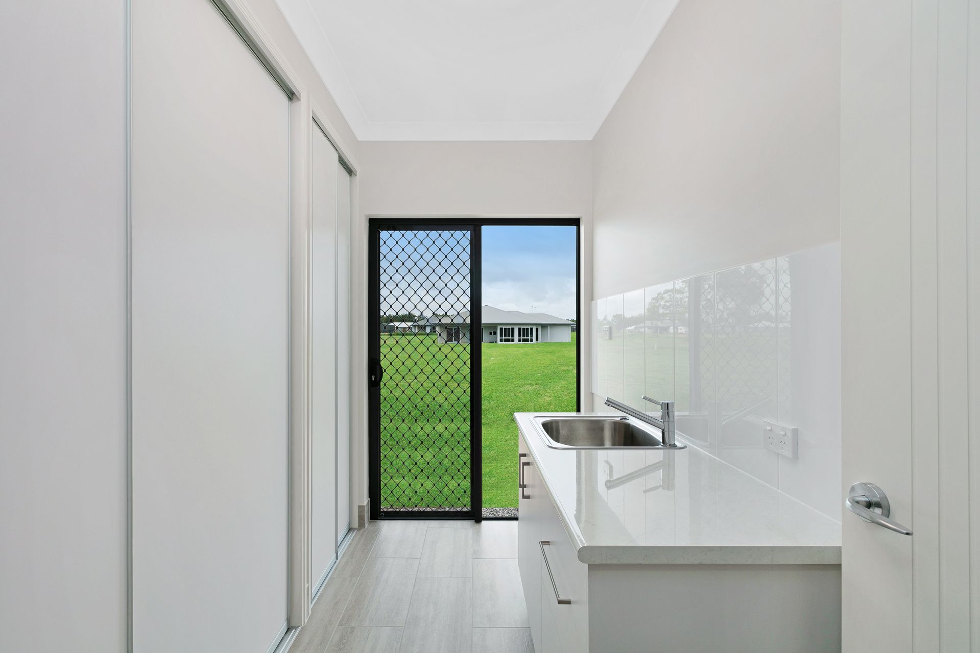 A Bright, Minimalist Laundry Room With White Cabinetry — Ashlee Jones Homes in Gordonvale, QLD