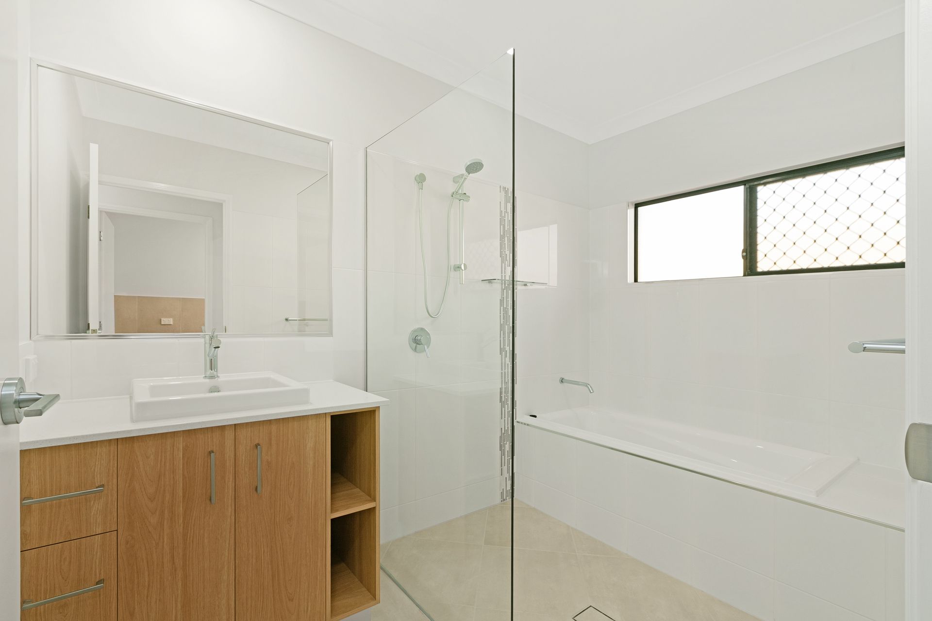 A Modern Bathroom Featuring a Wood Vanity With a White Sink — Ashlee Jones Homes in Gordonvale, QLD