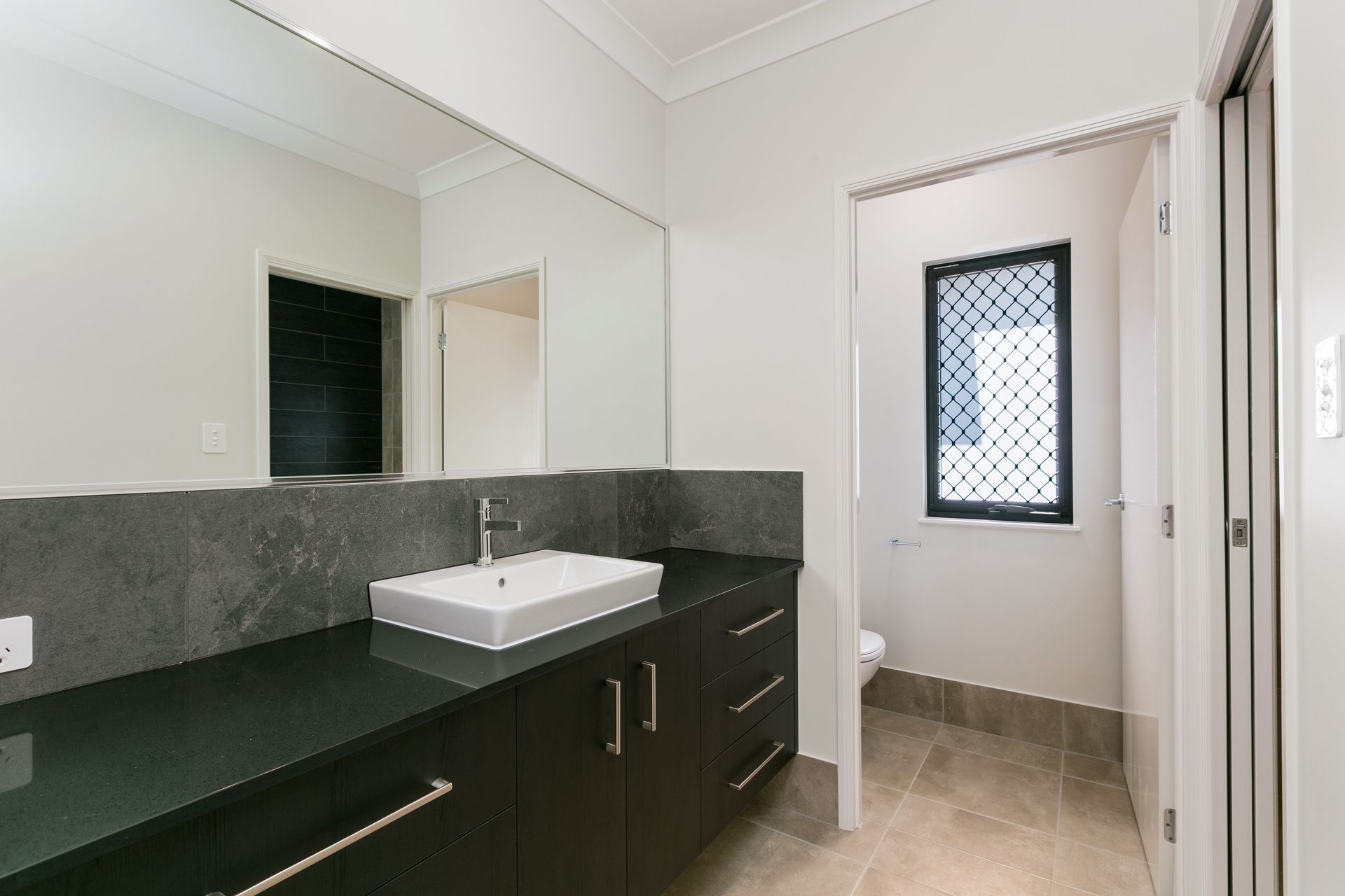 A Modern Bathroom Vanity With Dark Stone Counters — Ashlee Jones Homes in Gordonvale, QLD