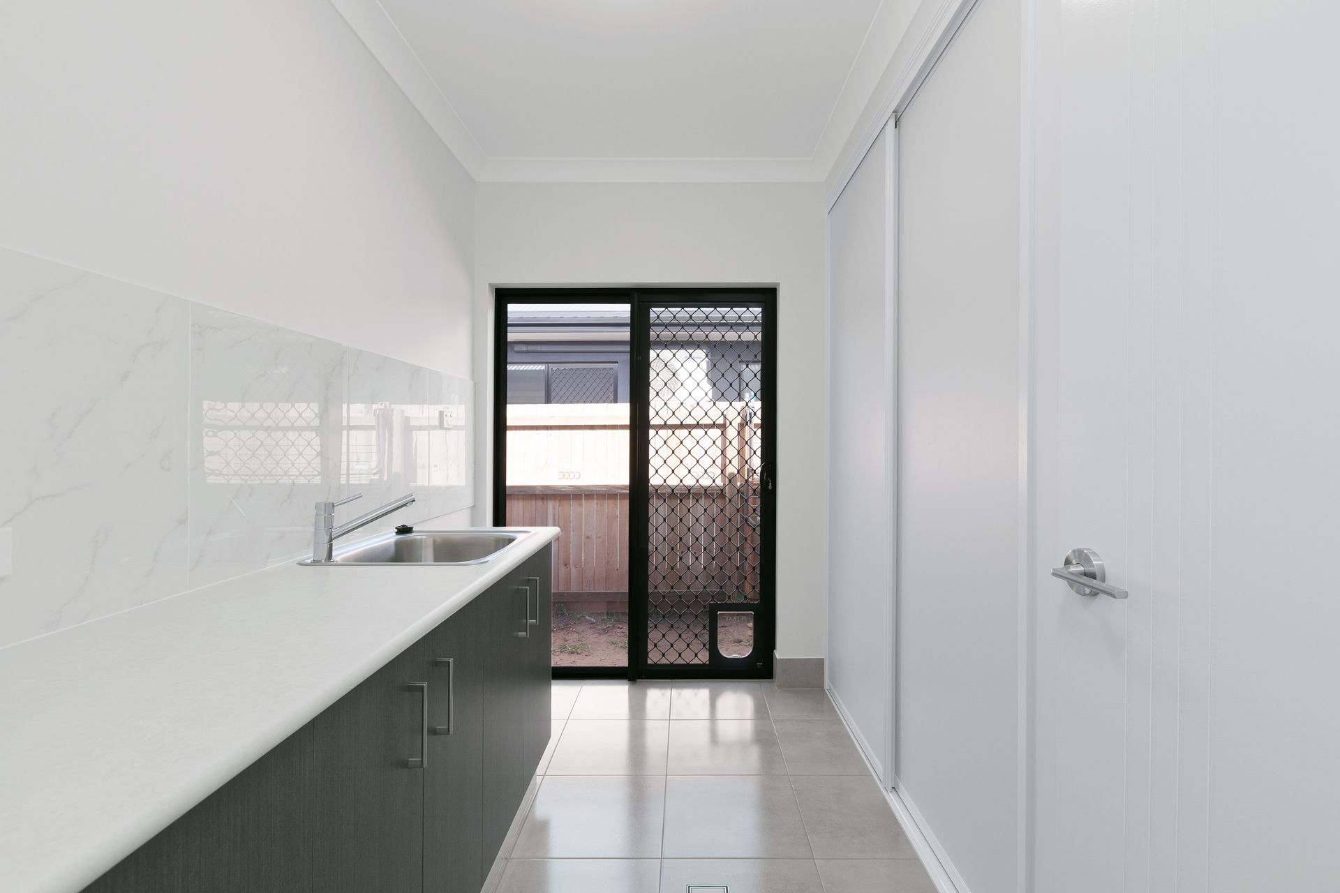 A Modern Galley-style Laundry Room With White Walls — Ashlee Jones Homes in Gordonvale, QLD