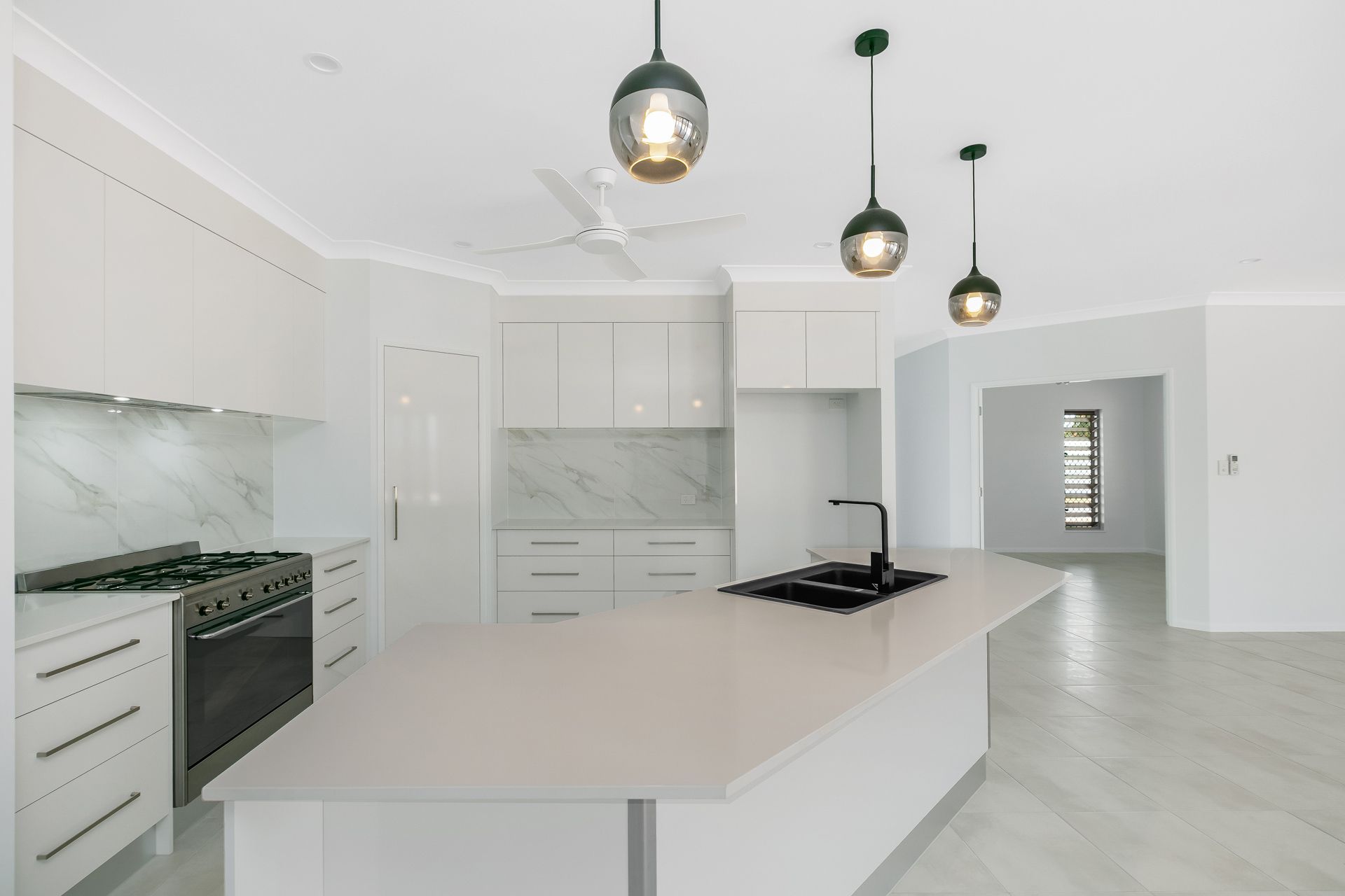 A Modern, White Kitchen Featuring a Large Island — Ashlee Jones Homes in Gordonvale, QLD