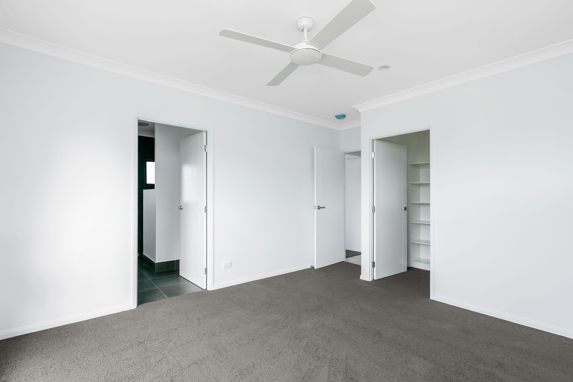 A Bright, Empty Bedroom With White Walls, Grey Carpeting — Ashlee Jones Homes in Gordonvale, QLD