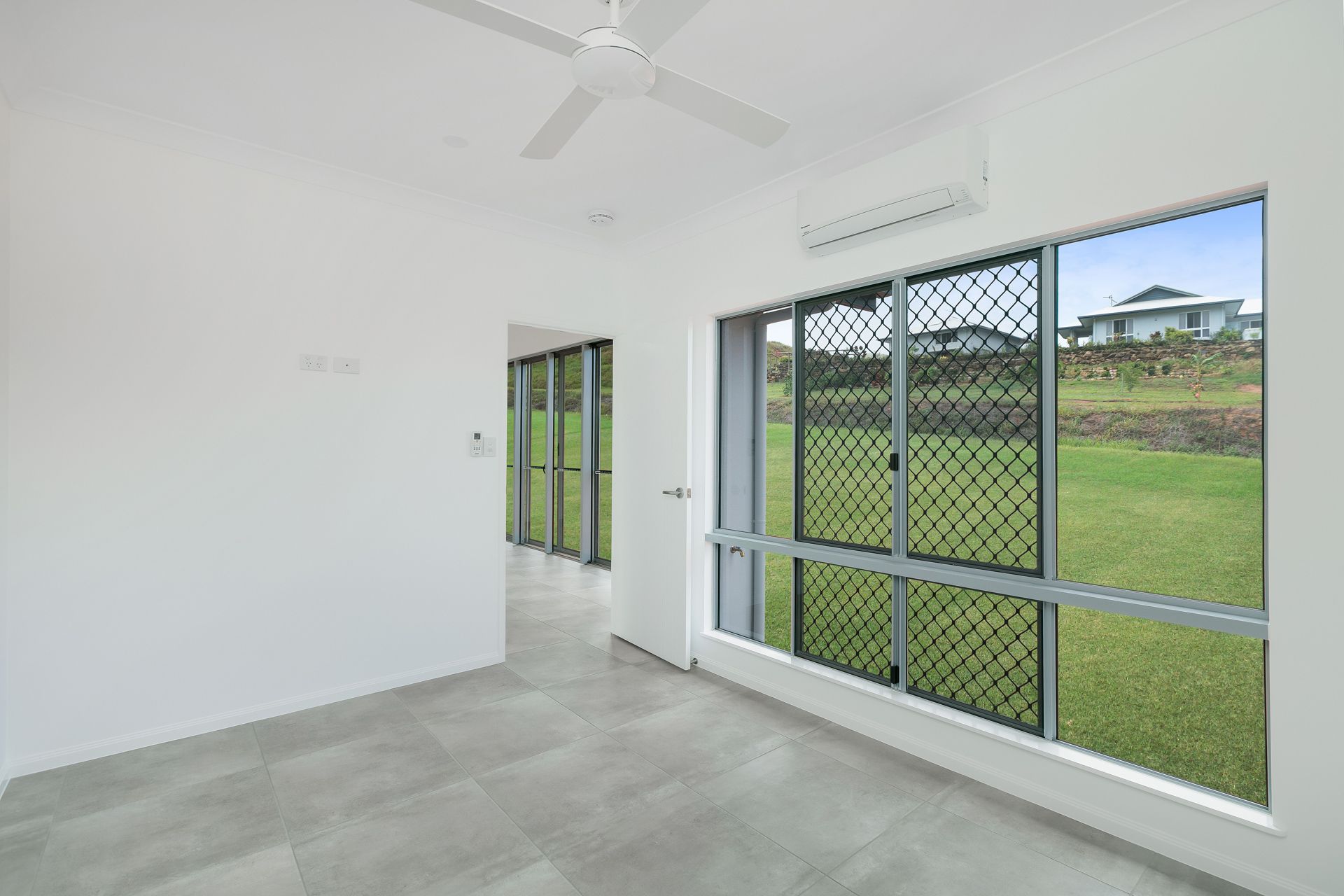A Bright, Empty Room With Grey Tiled Flooring — Ashlee Jones Homes in Gordonvale, QLD
