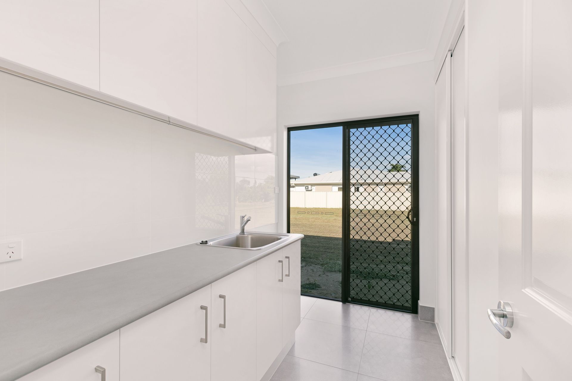 A Modern, Minimalist White Kitchen Laundry Room — Ashlee Jones Homes in Gordonvale, QLD
