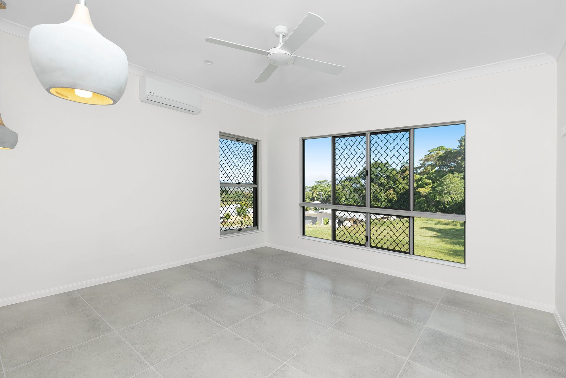 A Bright, Empty Room With White Walls, Grey Tiled Flooring — Ashlee Jones Homes in Gordonvale, QLD