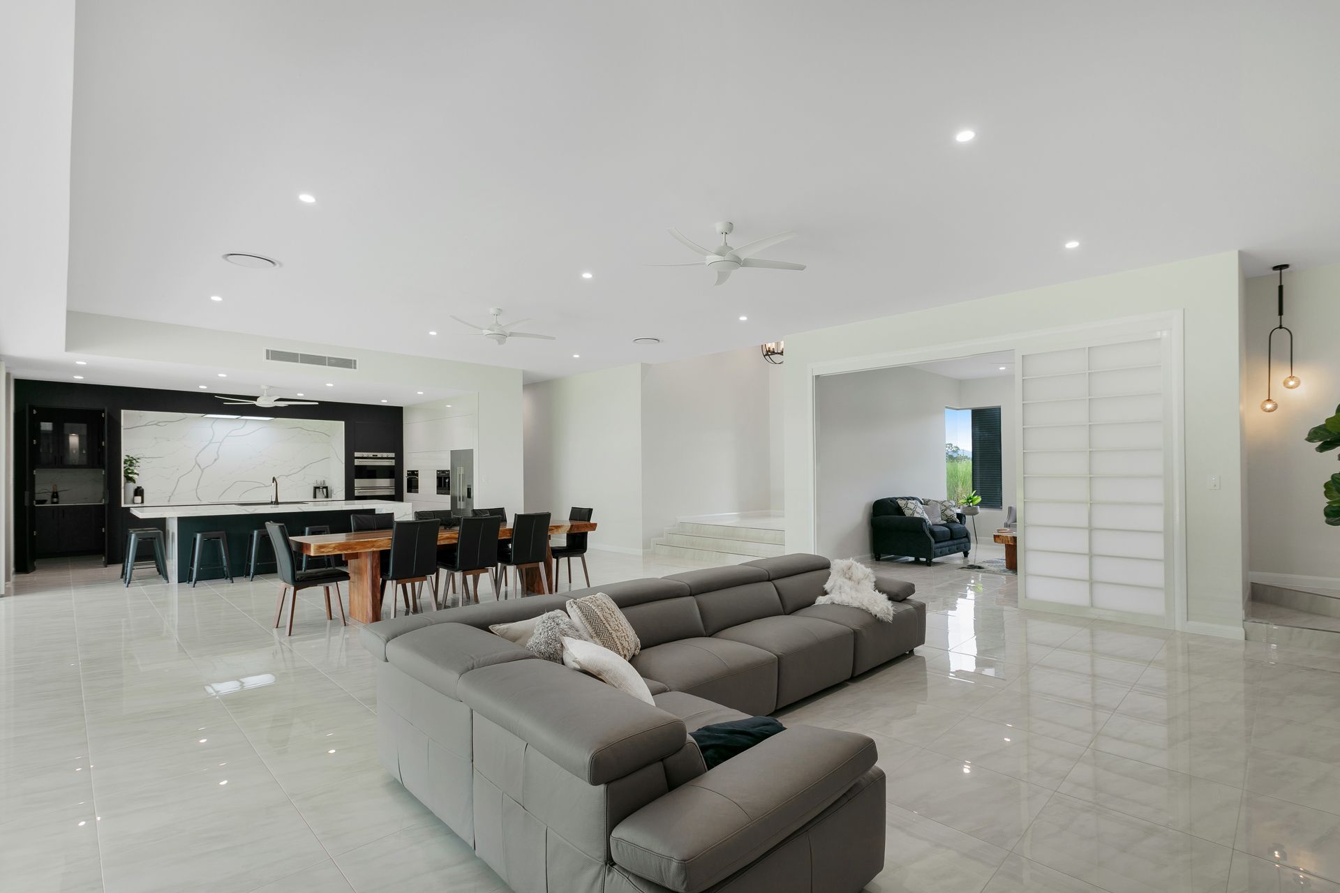 A Spacious, Modern Open-plan Home Featuring a Grey Sectional Sofa — Ashlee Jones Homes in Gordonvale, QLD