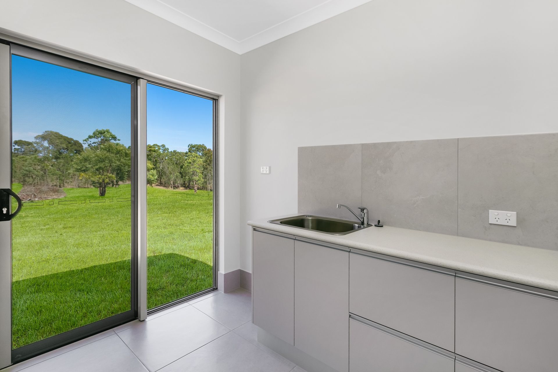 A Modern Laundry Room With Grey Cabinetry — Ashlee Jones Homes in Gordonvale, QLD