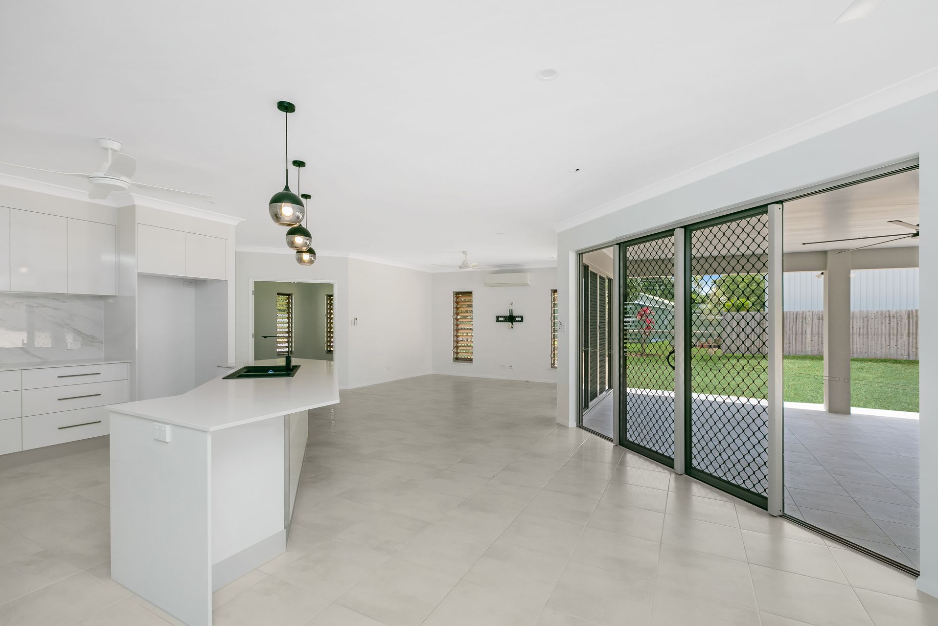 An Open-plan Kitchen and Living Space With a White Island — Ashlee Jones Homes in Gordonvale, QLD