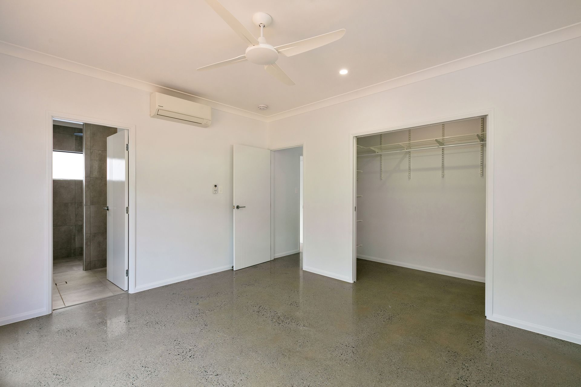 A Bright, Empty Bedroom With White Walls, Polished Concrete Floors — Ashlee Jones Homes in Gordonvale, QLD