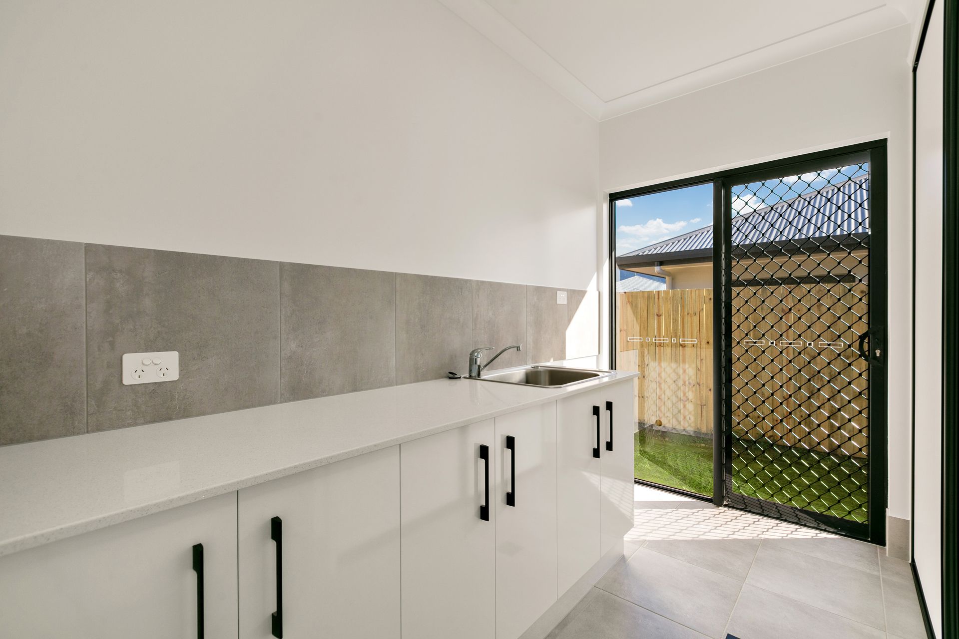 A Bright, Minimalist Laundry Room With White Cabinets — Ashlee Jones Homes in Gordonvale, QLD