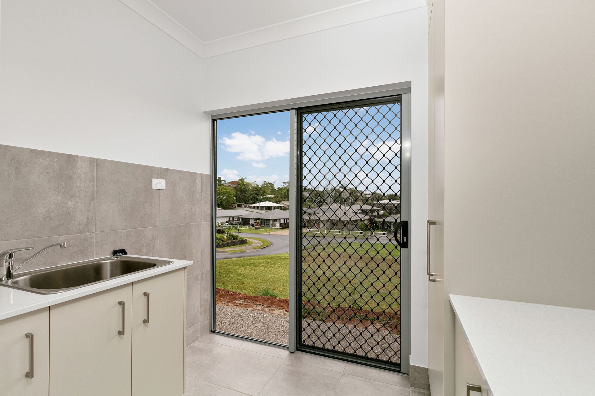 A Laundry Room With a Double Sink, Light Cabinets — Ashlee Jones Homes in Gordonvale, QLD