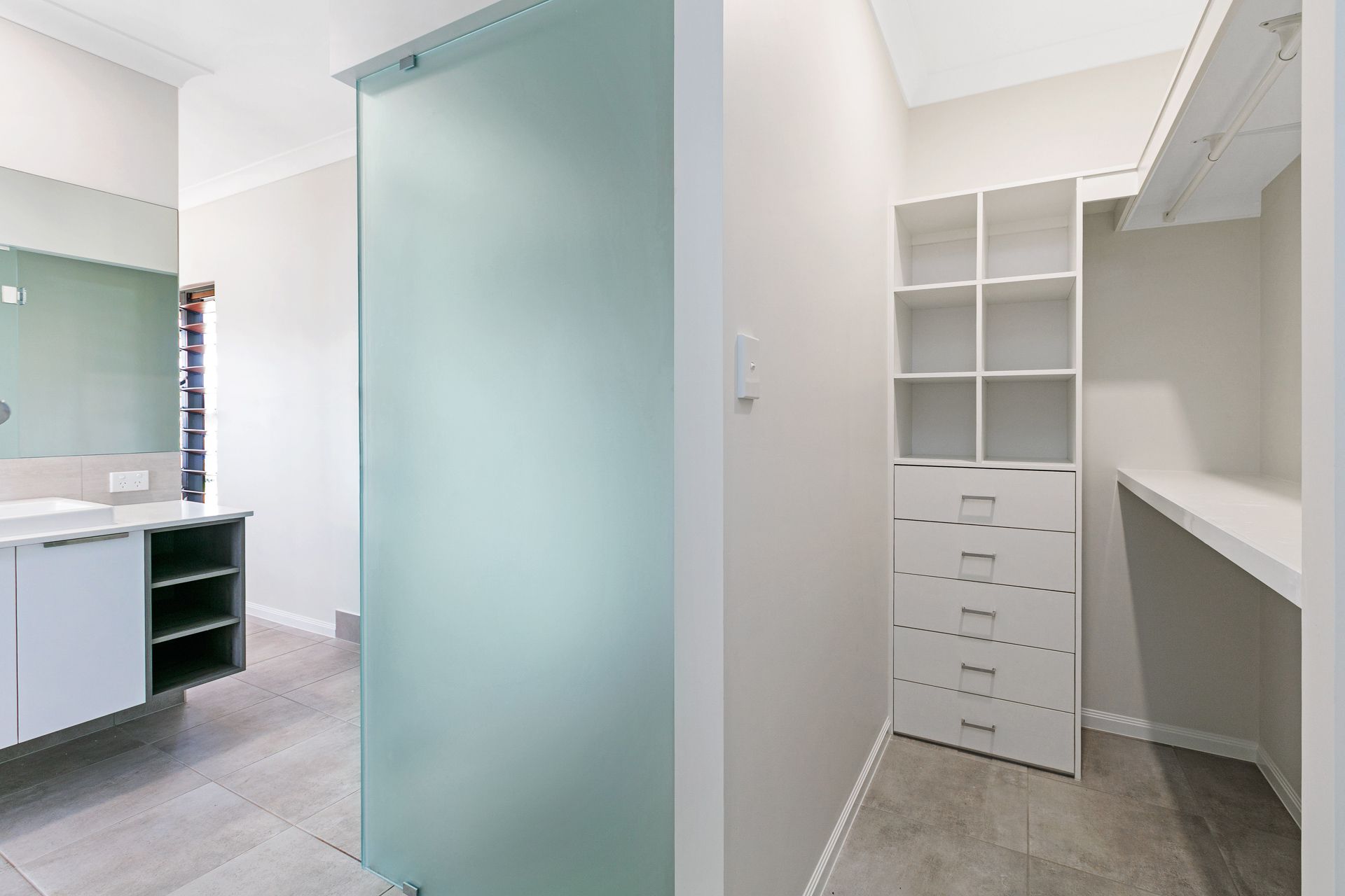 A Modern Bathroom Leads Into a Walk-in Closet With White Shelving — Ashlee Jones Homes in Gordonvale, QLD