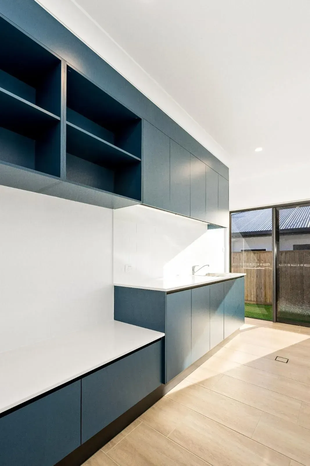 A Large Empty Room With Wooden Floors and White Walls — Ashlee Jones Homes in Gordonvale, QLD