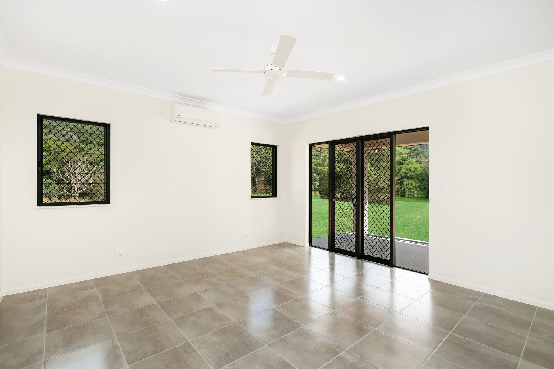 An Empty Room With Grey Tiled Floors, White Walls — Ashlee Jones Homes in Gordonvale, QLD