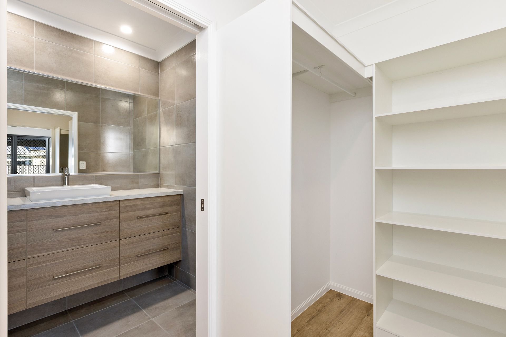 A Bathroom With a Wooden Vanity and Large Mirror — Ashlee Jones Homes in Gordonvale, QLD
