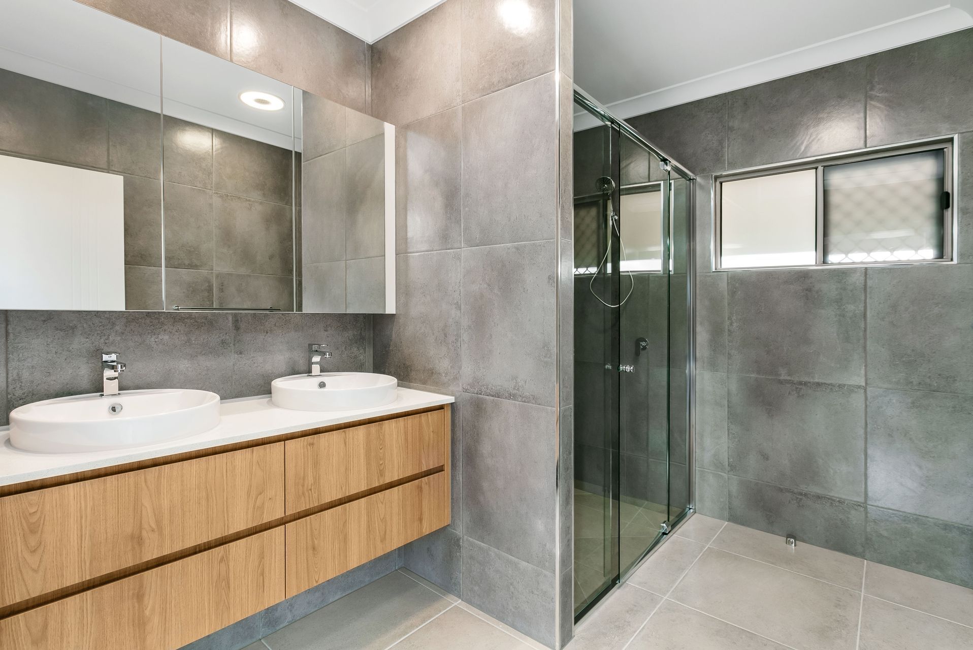 A Modern Bathroom With a Light Wood Floating Double Vanity — Ashlee Jones Homes in Gordonvale, QLD
