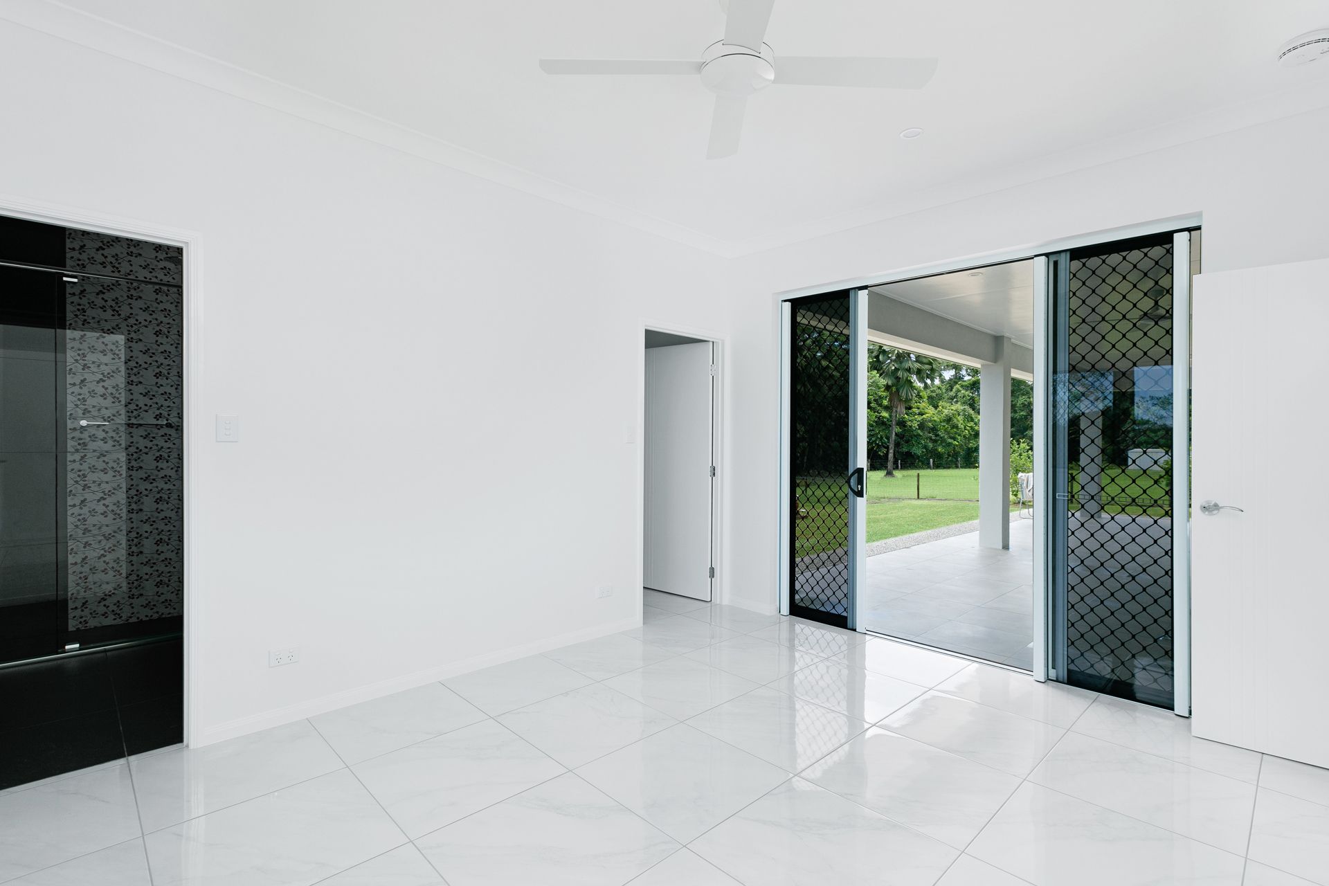 A Bright, Empty Room With White Walls and Glossy Tiled Floors — Ashlee Jones Homes in Gordonvale, QLD