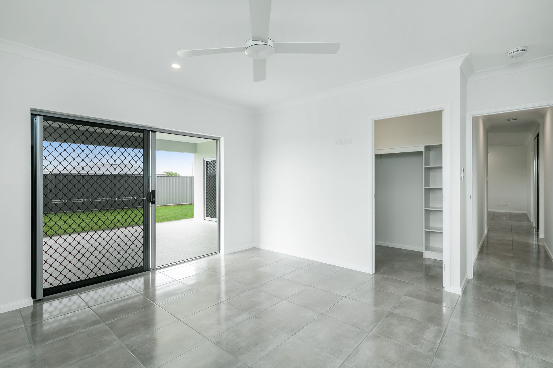 A Bright, Empty Room With Grey Tiled Flooring — Ashlee Jones Homes in Gordonvale, QLD