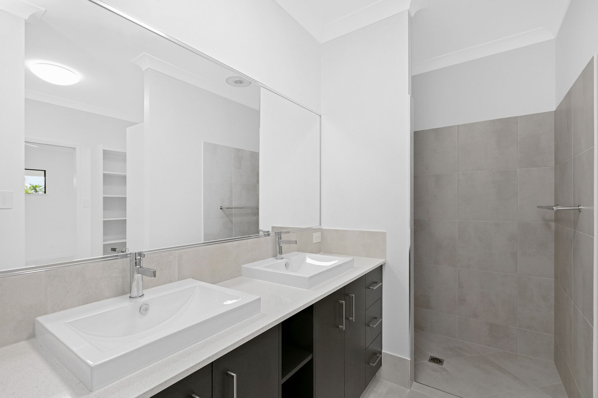 A Modern Bathroom Featuring a Dual-sink Vanity With Dark Cabinets — Ashlee Jones Homes in Gordonvale, QLD
