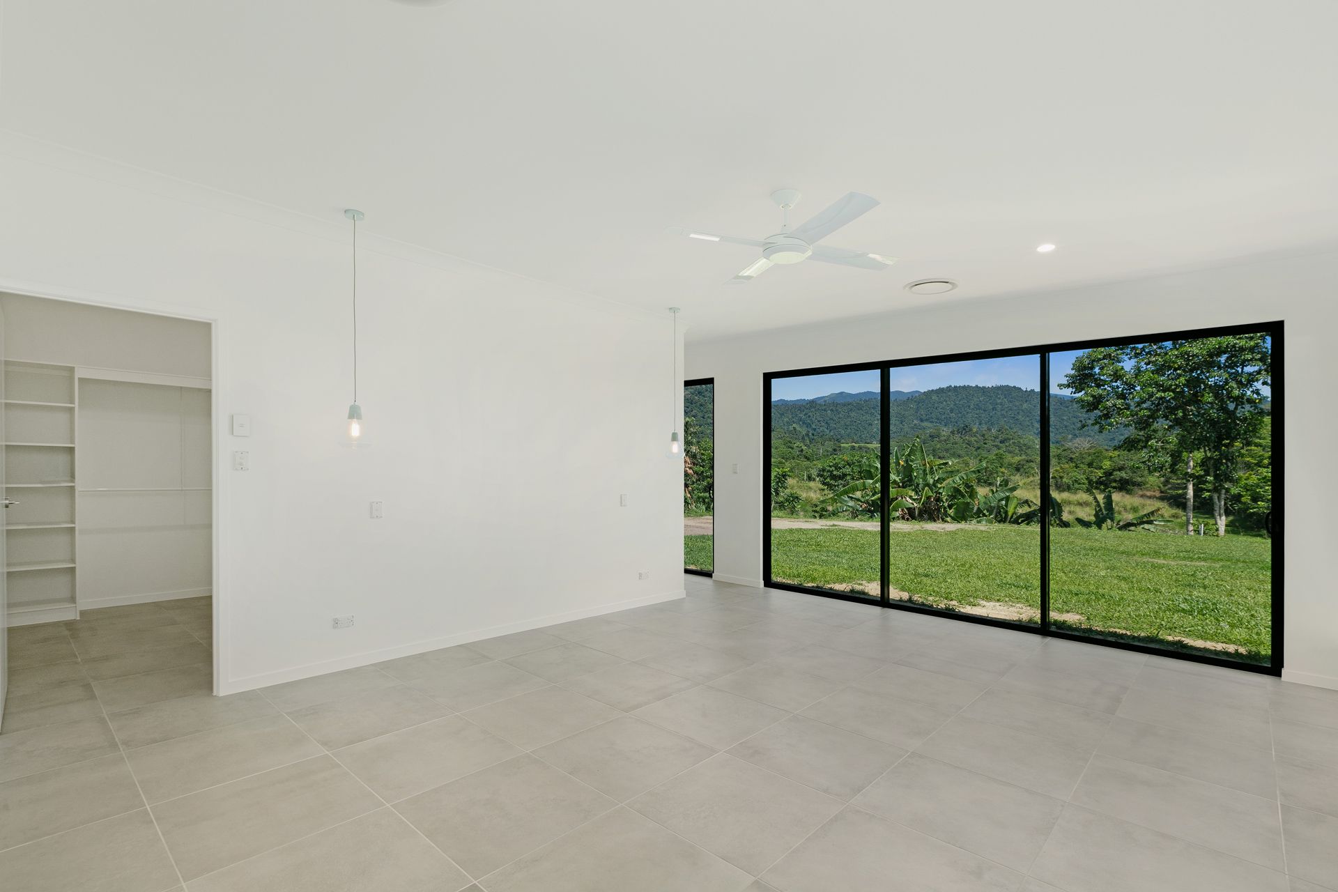 A Bright, Minimalist Room With White Walls, Large Floor-to-ceiling Glass Doors — Ashlee Jones Homes in Gordonvale, QLD