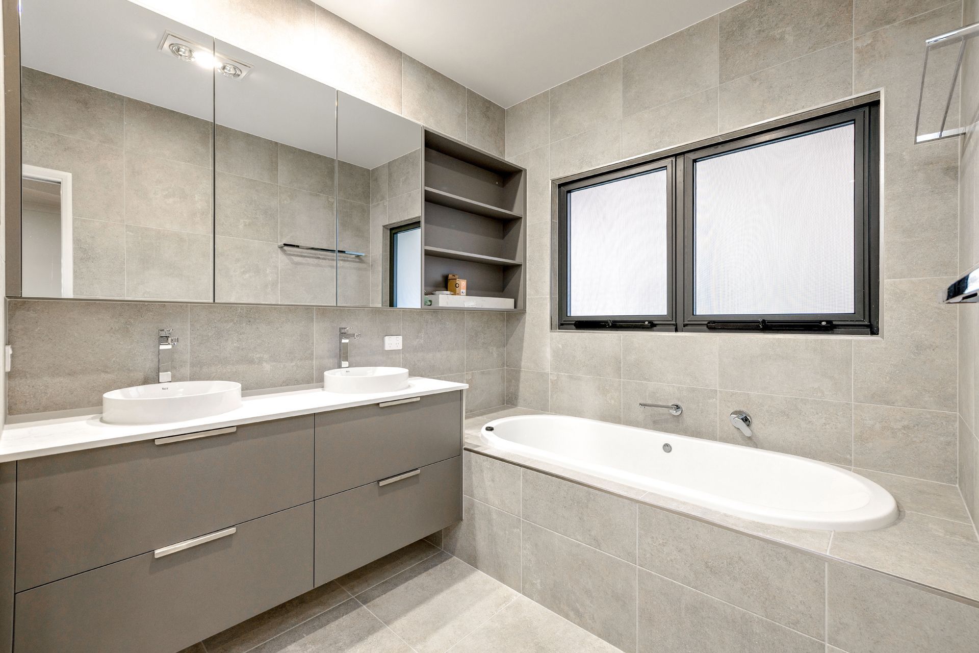 A Modern Bathroom With a Double Vanity, a Wide Mirror — Ashlee Jones Homes in Gordonvale, QLD