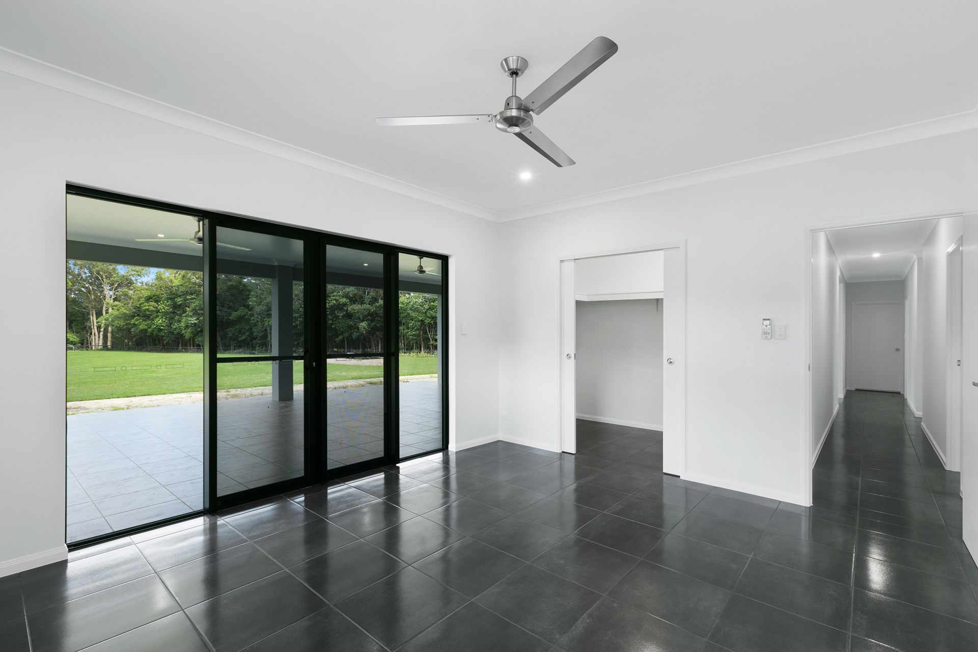 A Minimalist Room With White Walls, Dark Tiled Floors — Ashlee Jones Homes in Gordonvale, QLD