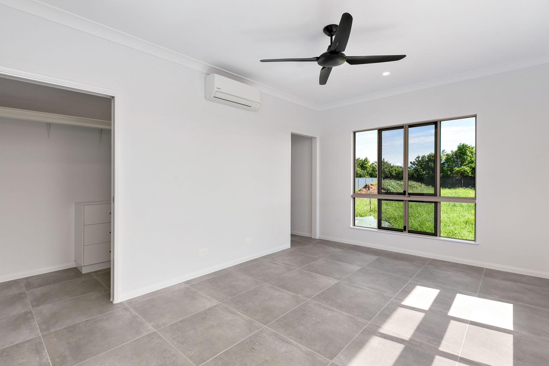 An Unfurnished Room With White Walls, Grey Tiled Flooring — Ashlee Jones Homes in Gordonvale, QLD