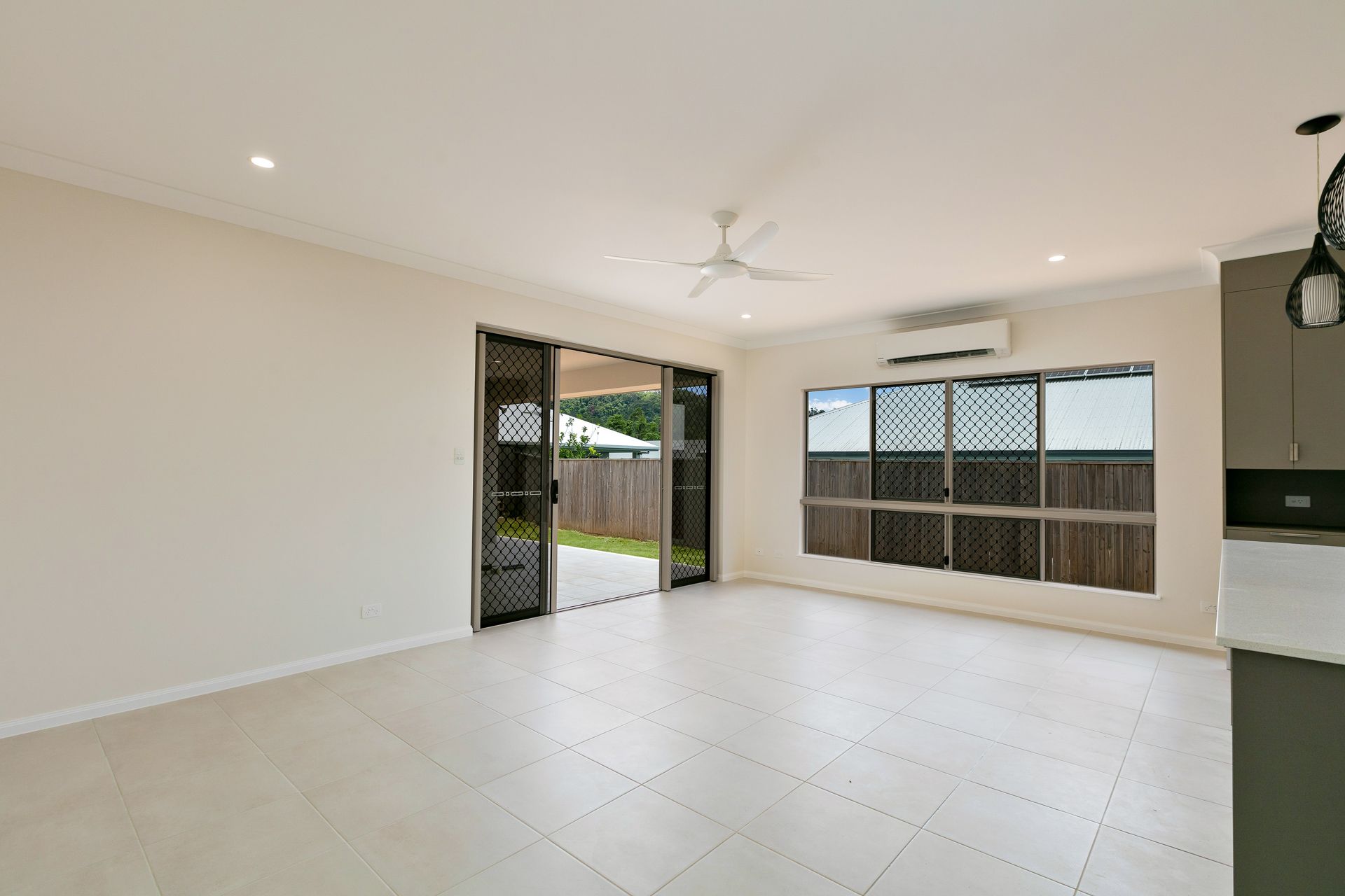 An Empty, Bright Living Area With Light-colored Tile Floors — Ashlee Jones Homes in Gordonvale, QLD