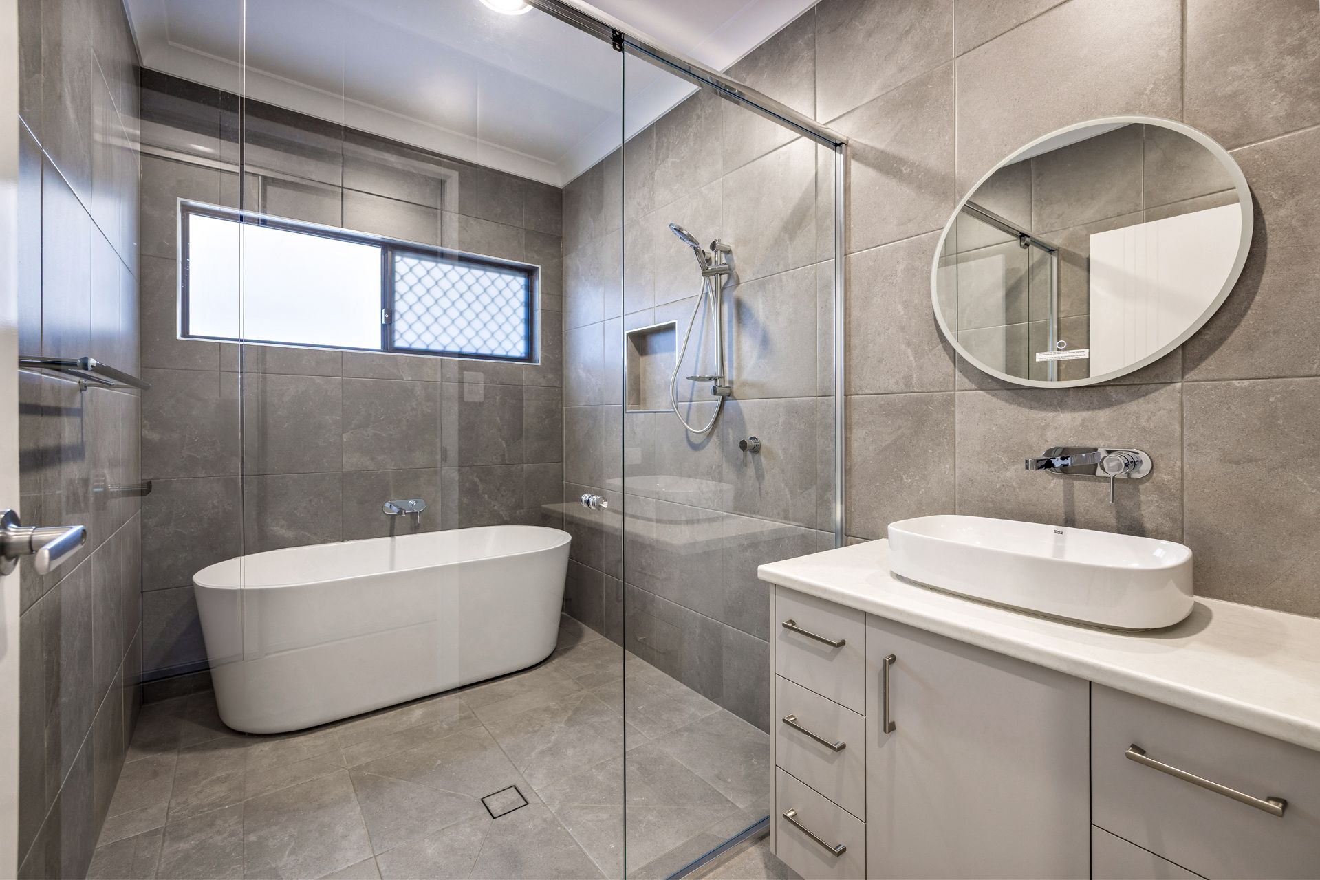 A Modern Bathroom Featuring a White Freestanding Bathtub — Ashlee Jones Homes in Gordonvale, QLD