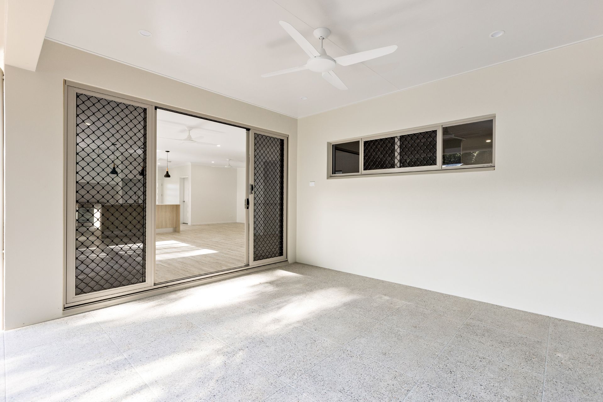 A Bright, Covered Patio With White Walls, a Ceiling Fan — Ashlee Jones Homes in Gordonvale, QLD