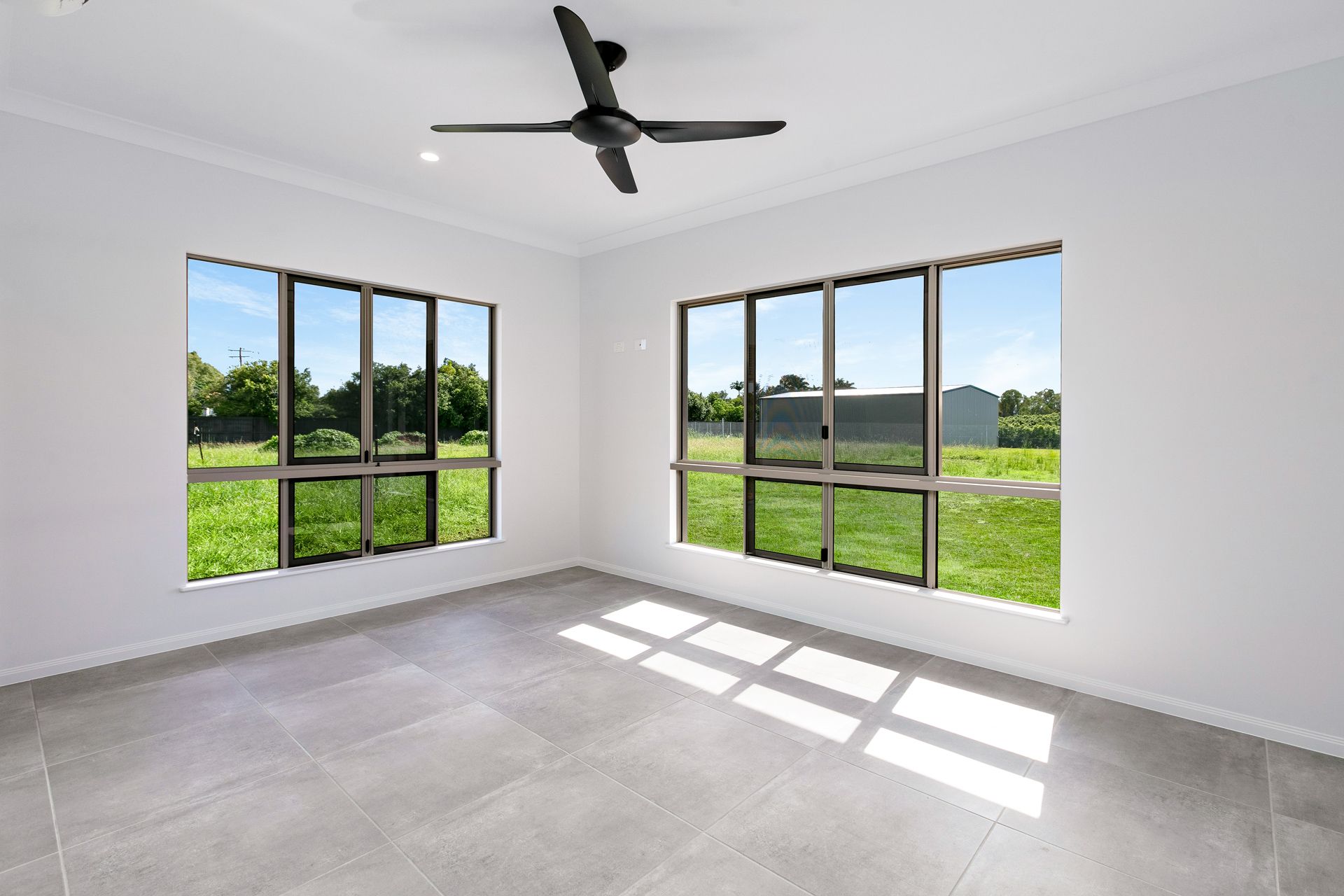A Bright, Empty Room With Grey Tiled Floors — Ashlee Jones Homes in Gordonvale, QLD