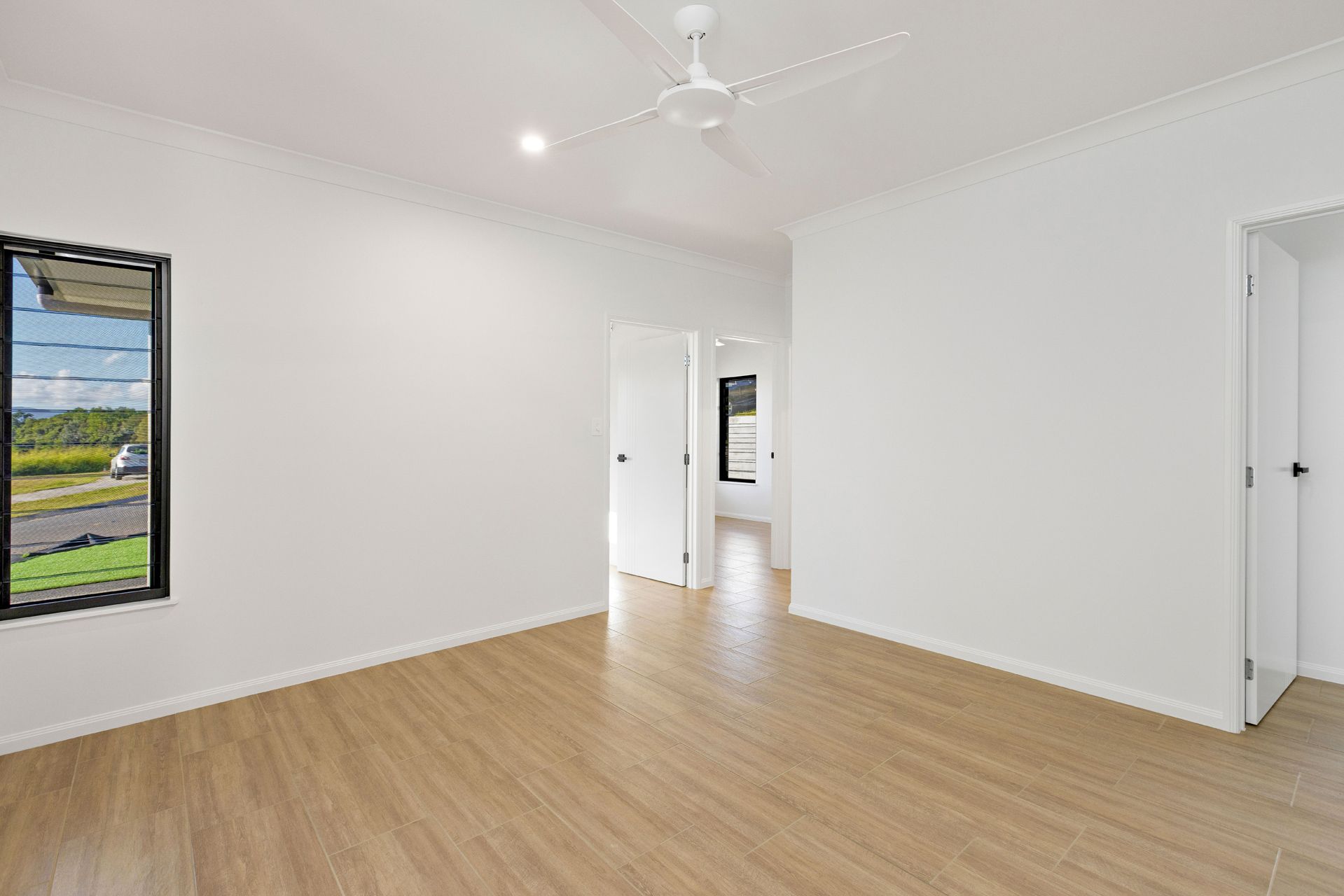 An Empty, White-walled Room With Light Wood-look Flooring — Ashlee Jones Homes in Gordonvale, QLD