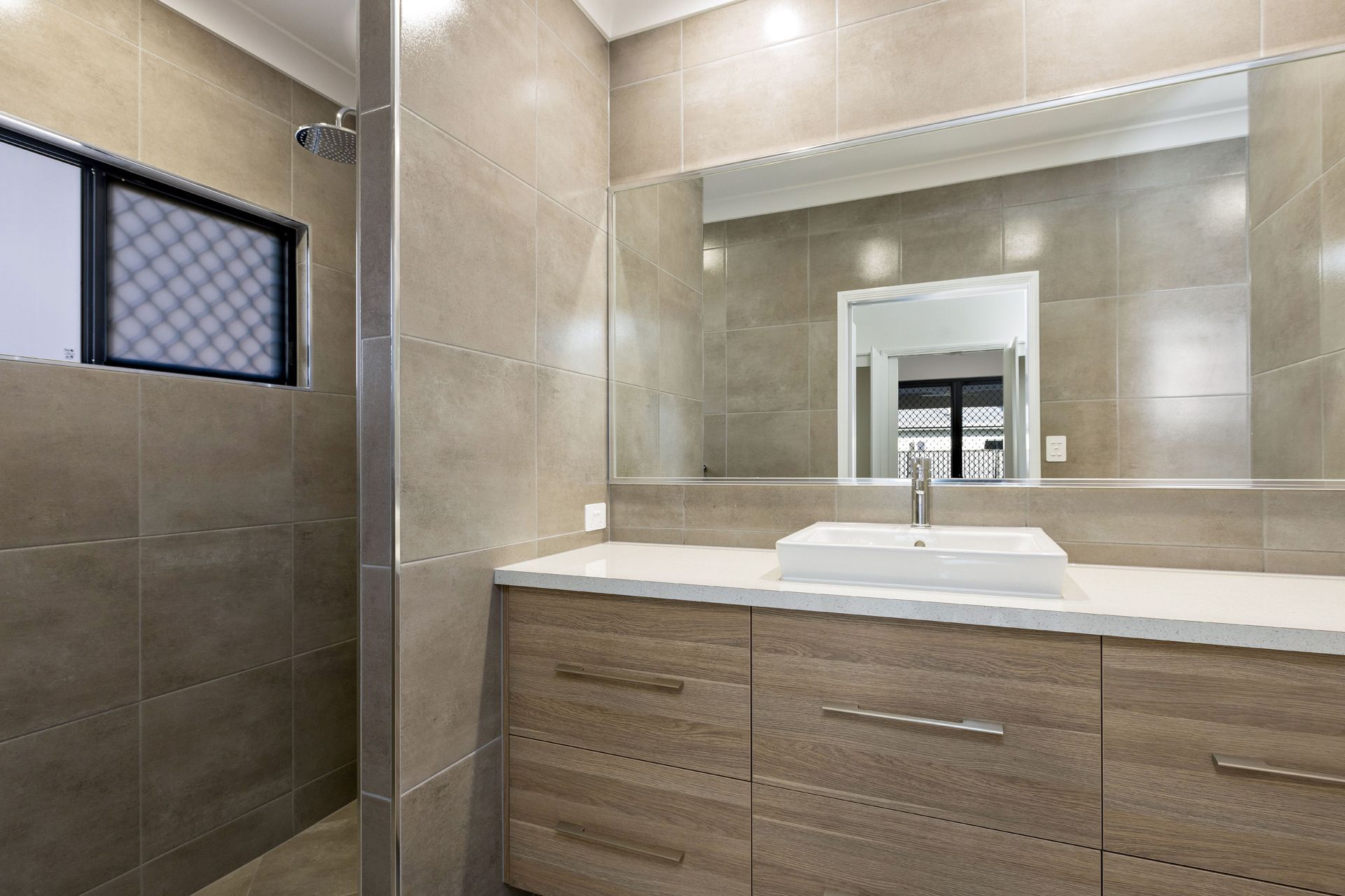 A Modern Bathroom With a Light Wood Vanity — Ashlee Jones Homes in Gordonvale, QLD
