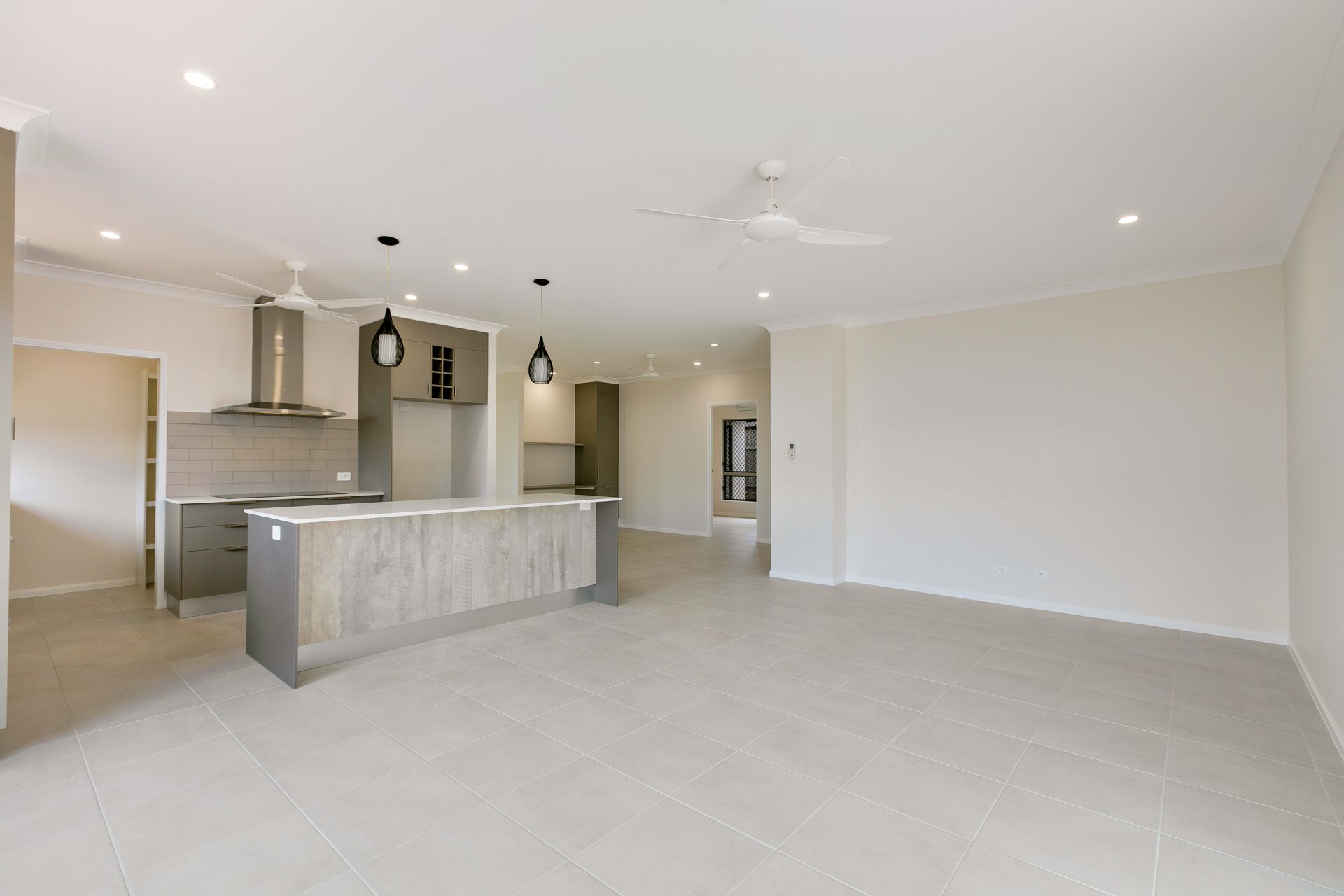 A Modern Open-plan Interior Featuring a Gray Kitchen Island — Ashlee Jones Homes in Gordonvale, QLD