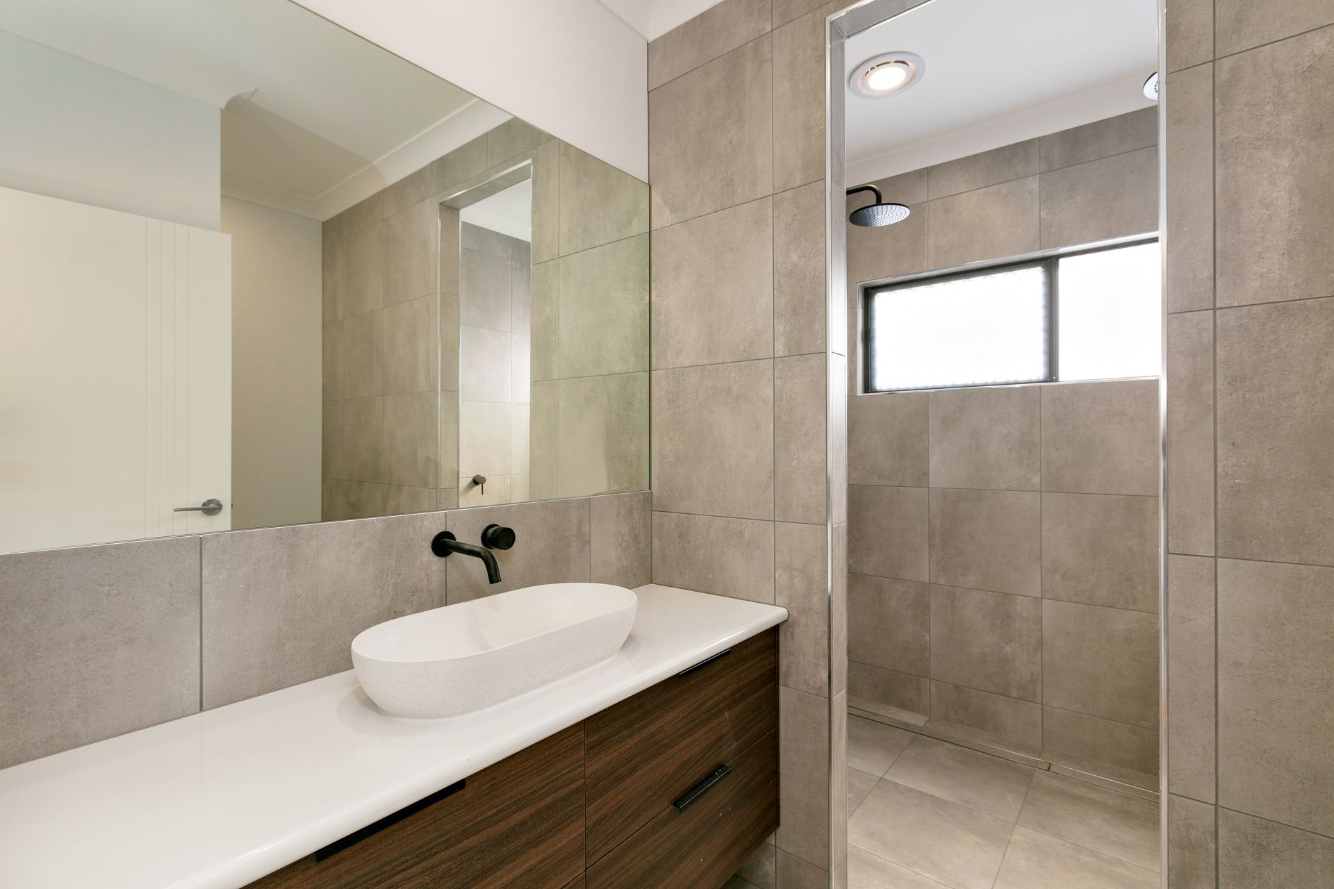 A Modern Bathroom With a White Vessel Sink on a Wood Vanity — Ashlee Jones Homes in Gordonvale, QLD