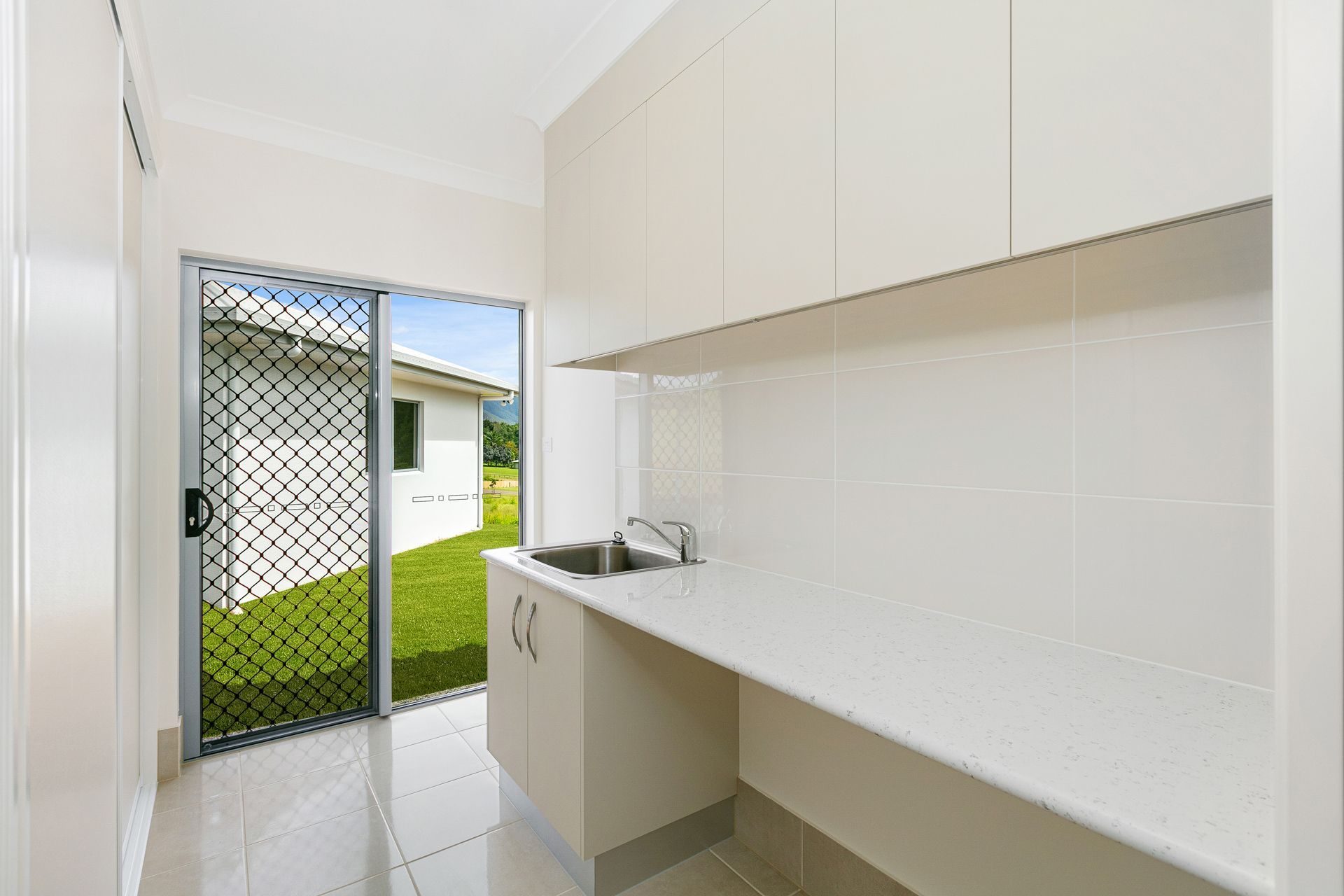 A Clean, Modern Laundry Room With White Cabinetry — Ashlee Jones Homes in Gordonvale, QLD