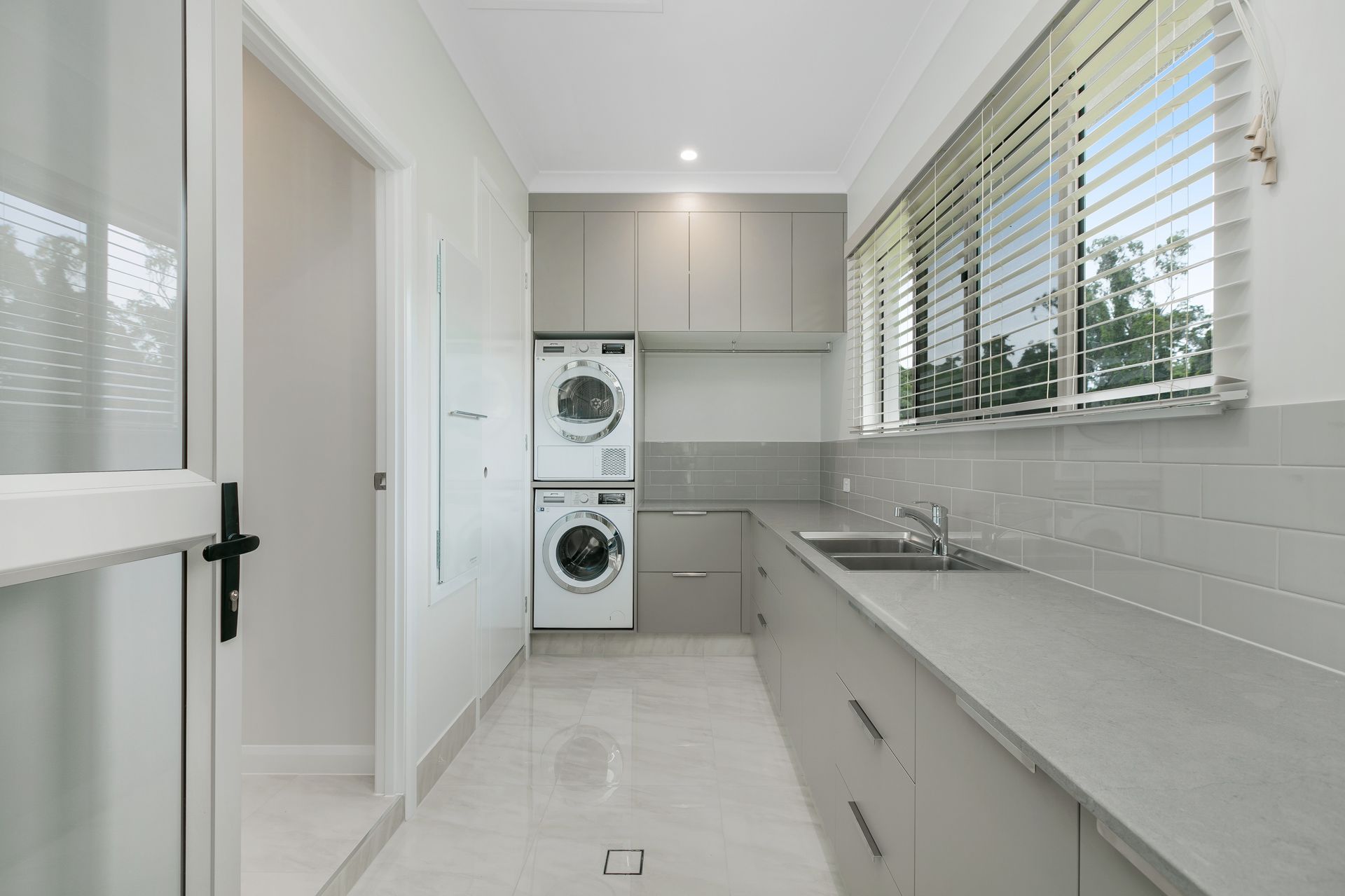Modern Laundry Room With Gray Cabinets, White Tiled Floors — Ashlee Jones Homes in Gordonvale, QLD