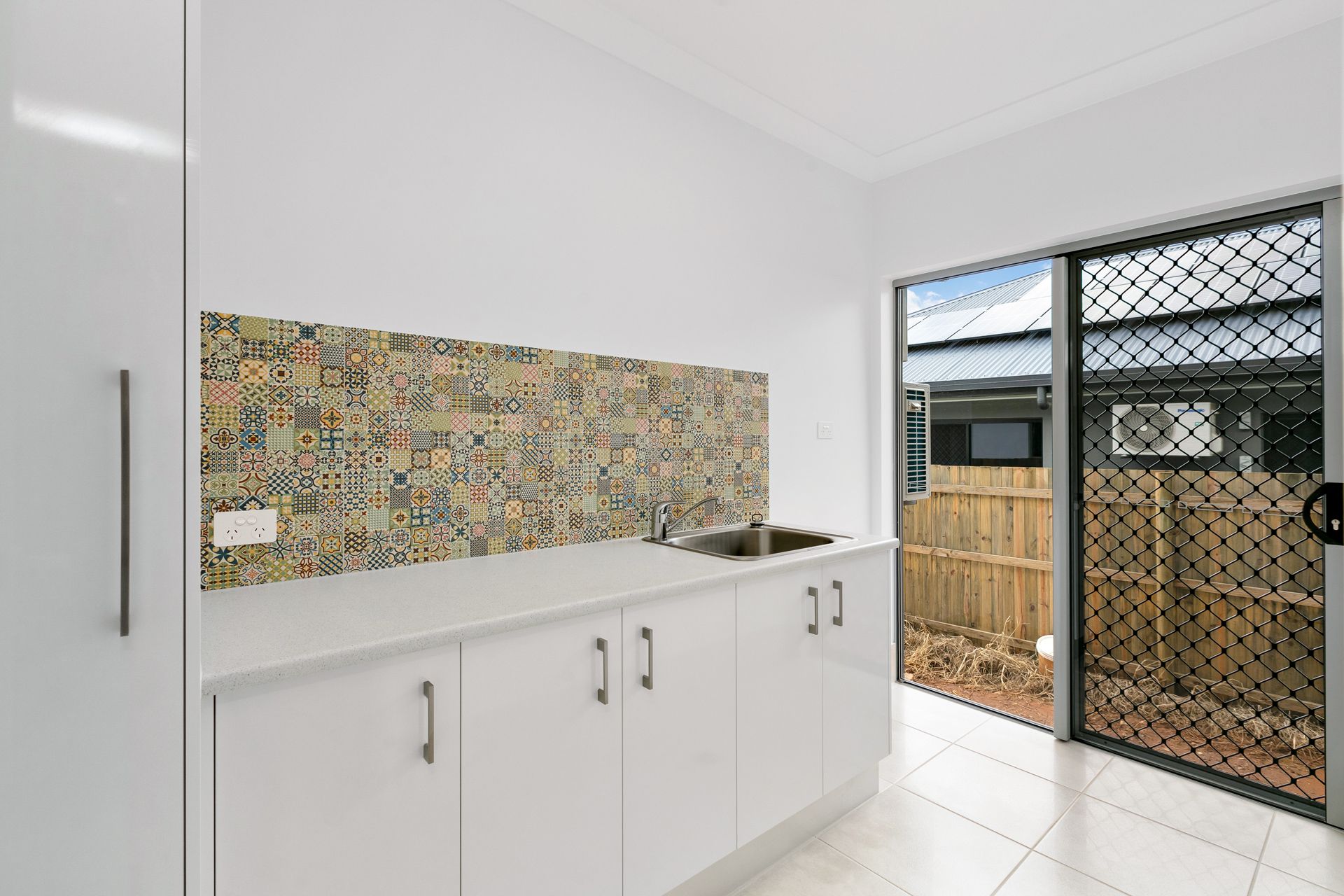 A White Kitchen Cabinet With a Patterned Backsplash — Ashlee Jones Homes in Gordonvale, QLD