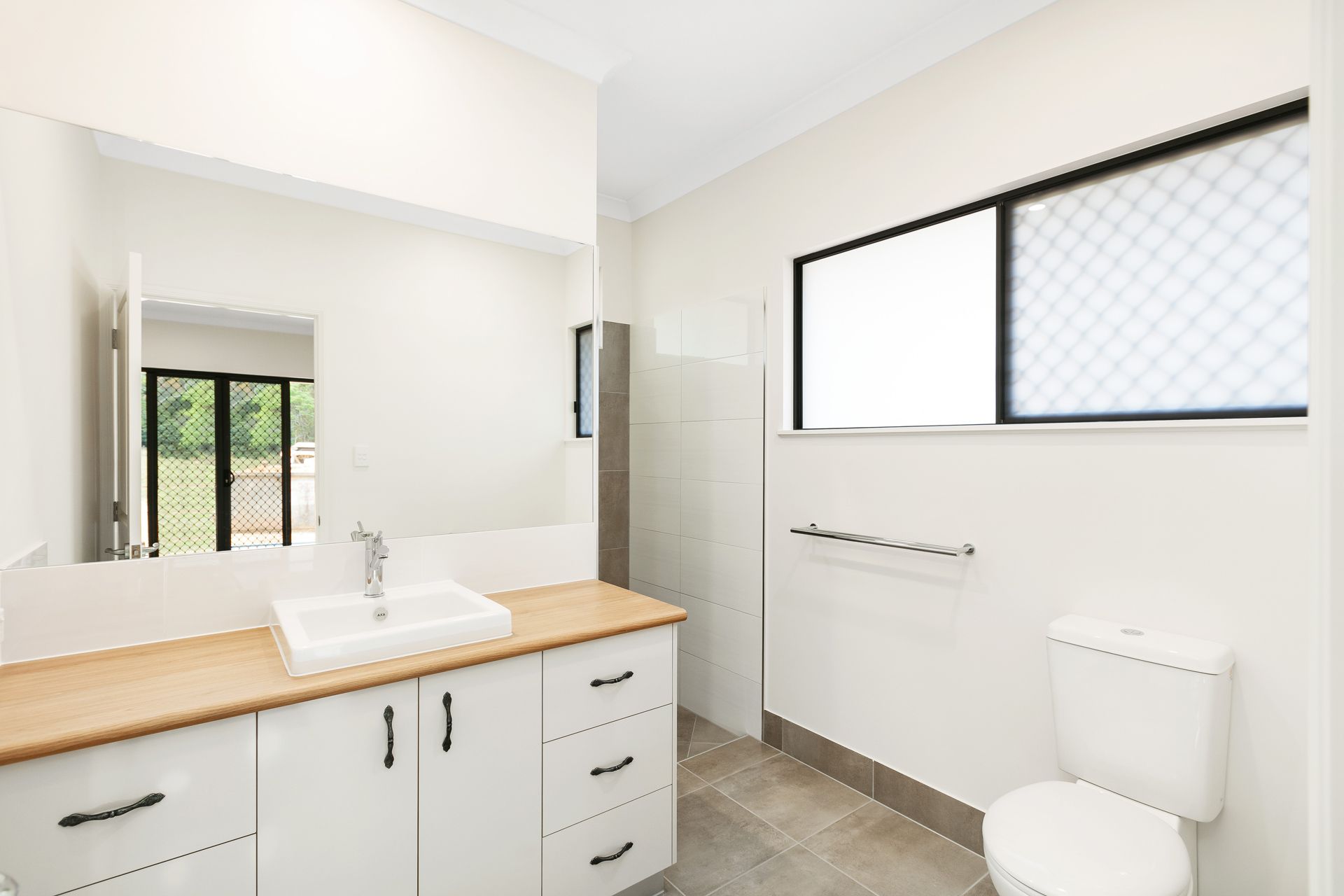 A Modern, Bright Bathroom With White Cabinets — Ashlee Jones Homes in Gordonvale, QLD