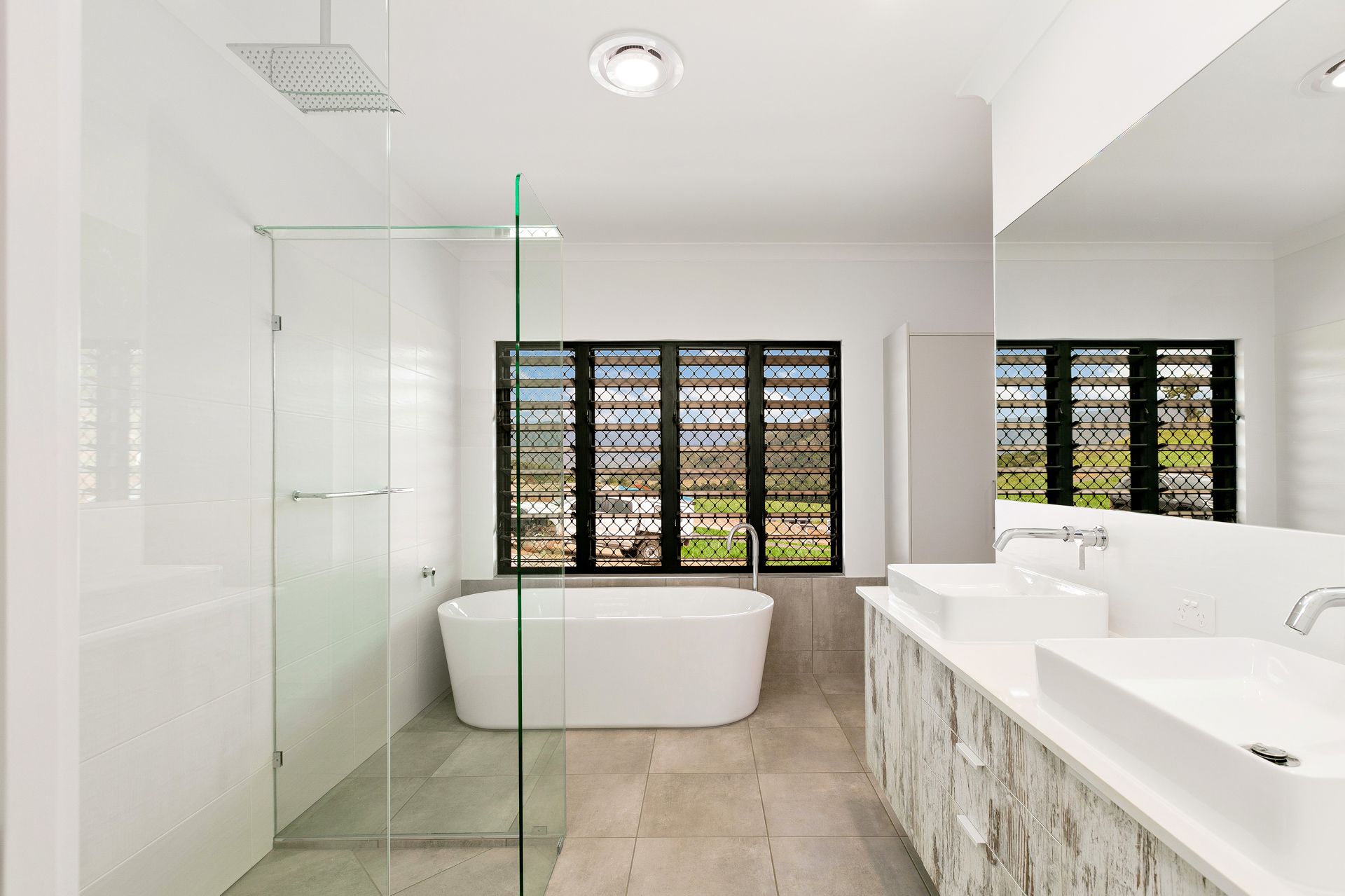 A Modern Bathroom With a Double Vanity, a Freestanding Tub — Ashlee Jones Homes in Gordonvale, QLD